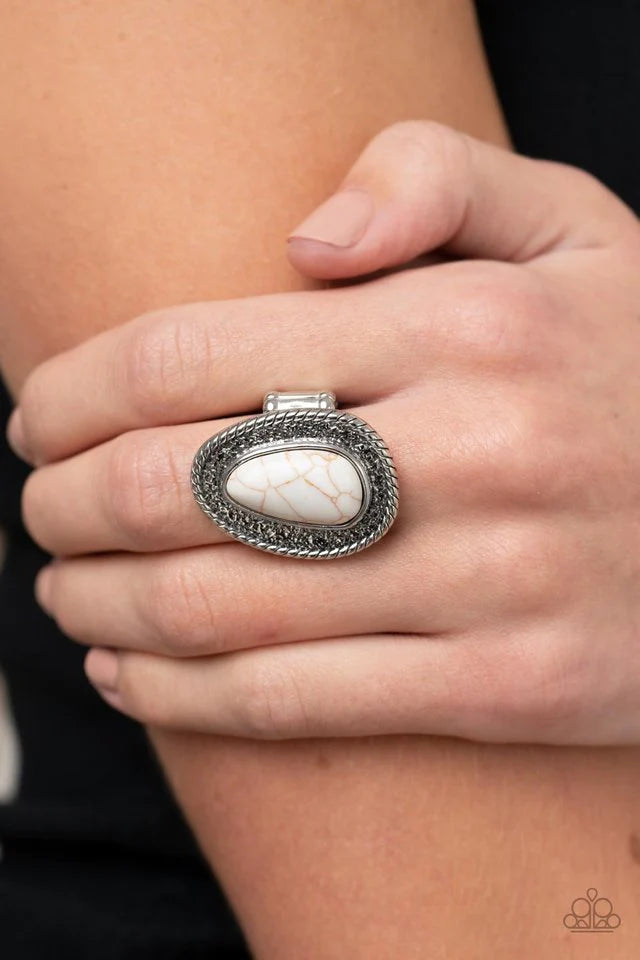 Paparazzi Accessories Downtown Desertscape - White An asymmetrical white stone imperfectly adorns the center of a hammered silver frame bordered in spun silver detail, resulting in a radiant rustic centerpiece atop the finger. Features a stretchy band for