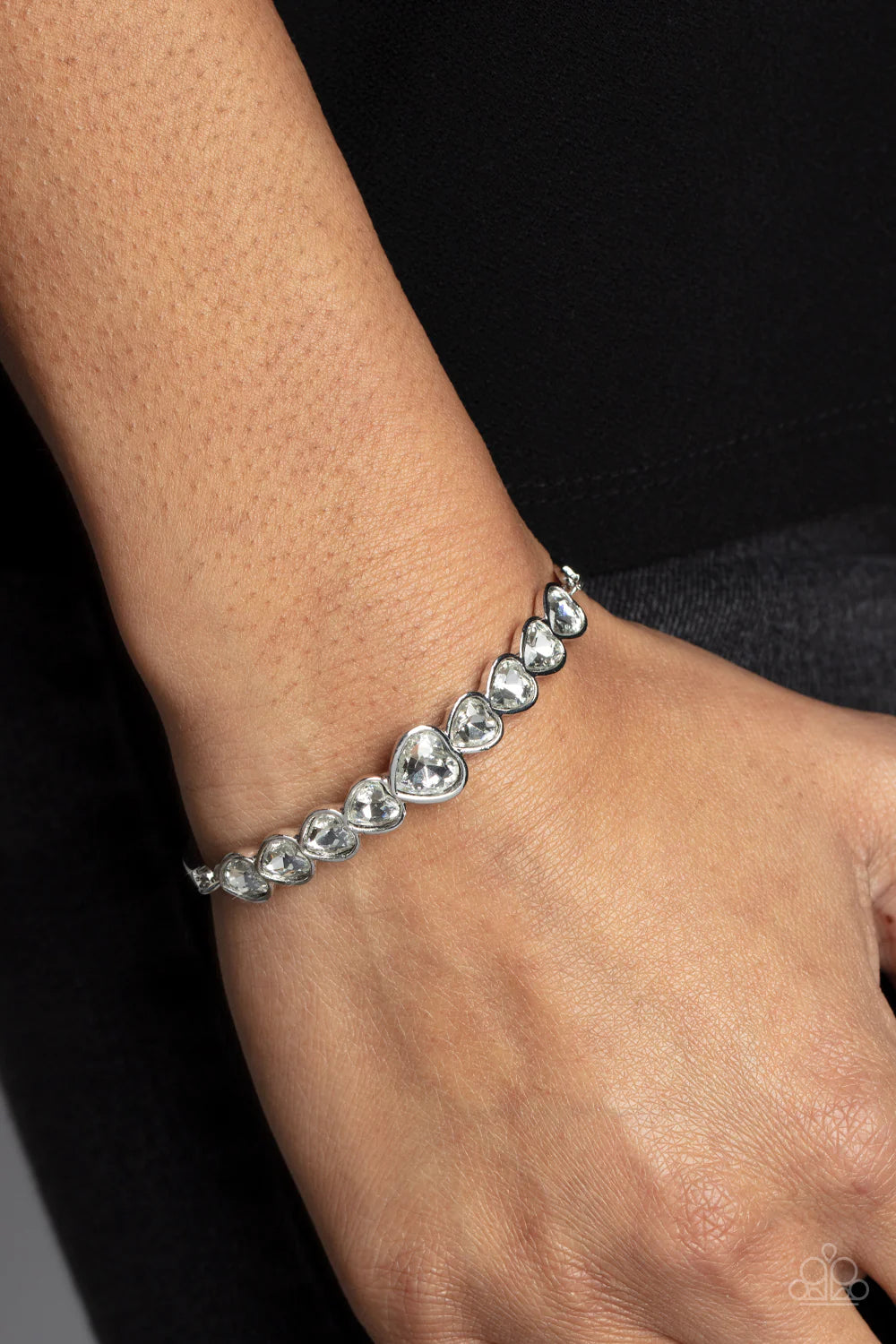 Paparazzi Accessories Lusty Luster - White Attached to silver bars, a sparkling series of heart cut white gems are encased in glistening silver frames that curve into a flirtatious centerpiece atop the wrist. Features an adjustable clasp closure. Sold as