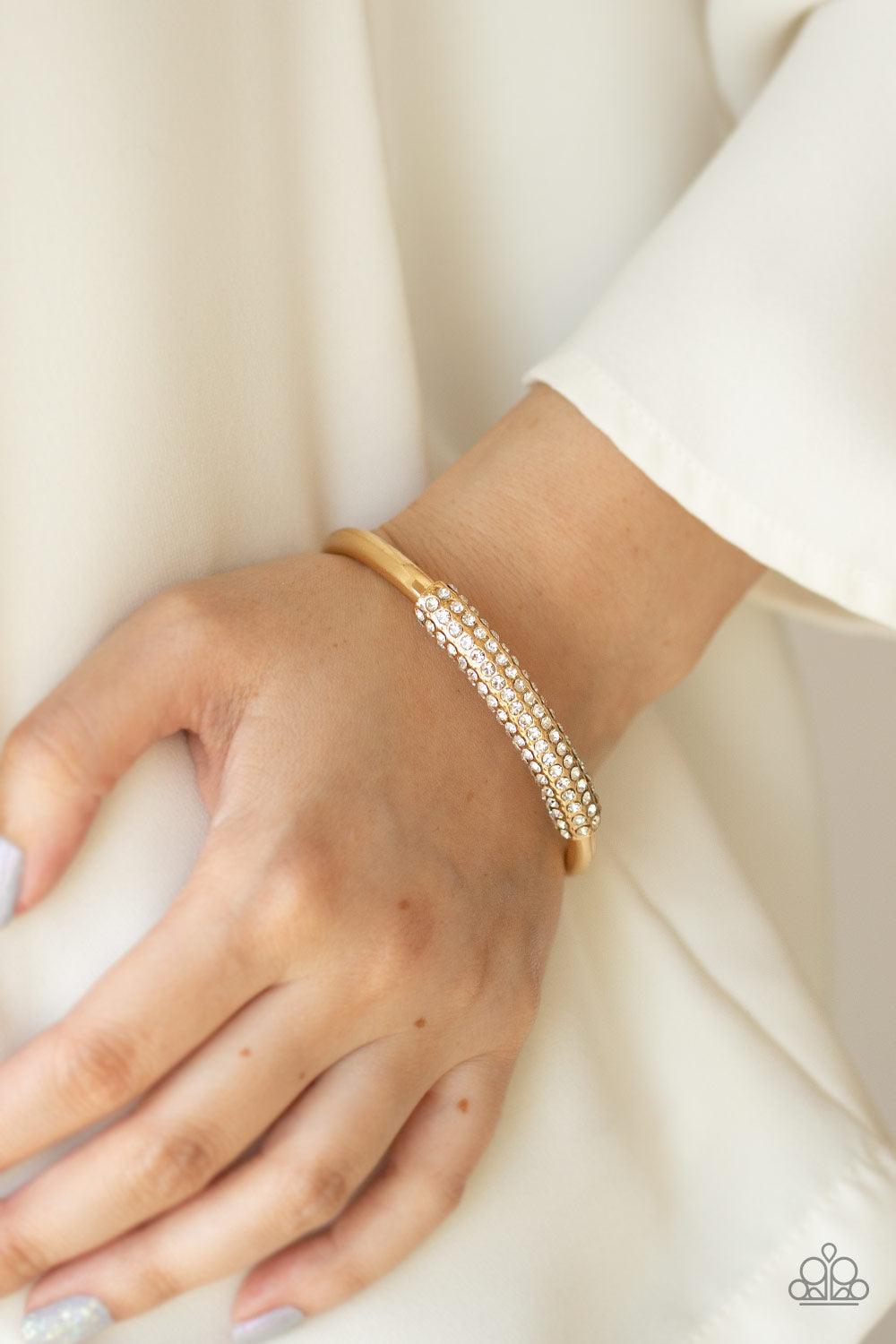 Paparazzi Accessories Day to Day Dazzle - Gold The center of a thick bangle-like cuff is decorated in a sleek gold frame encrusted in row after row of glassy white rhinestones for a refined flair. Sold as one individual bracelet. Jewelry