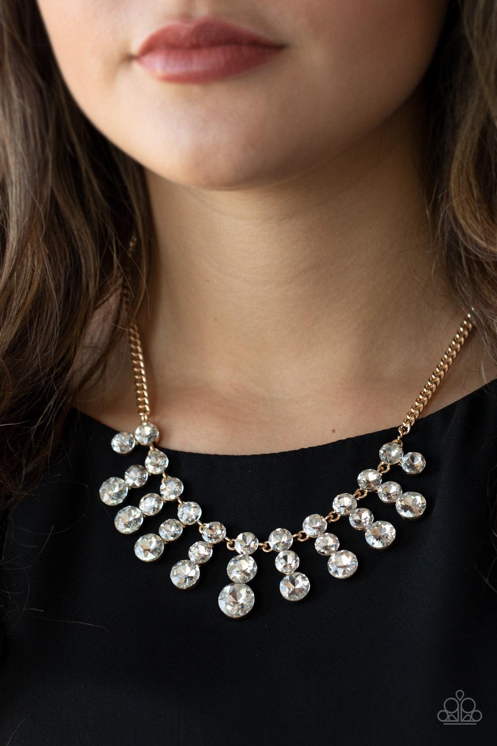 Paparazzi Accessories Celebrity Couture - Gold Glittery stacks of glassy white rhinestones gradually increase in size as they drip from the bottom of a classic gold chain, creating a blinding fringe below the collar. Features an adjustable clasp closure.