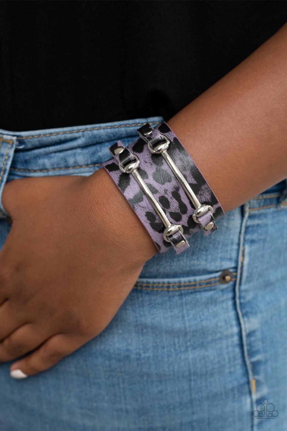 Paparazzi Accessories Safari Scene - Purple Two arcing silver bars are studded in place across the front of a thick leather band painted in purple and black cheetah print for a wild look. Features an adjustable snap closure. Sold as one individual bracele