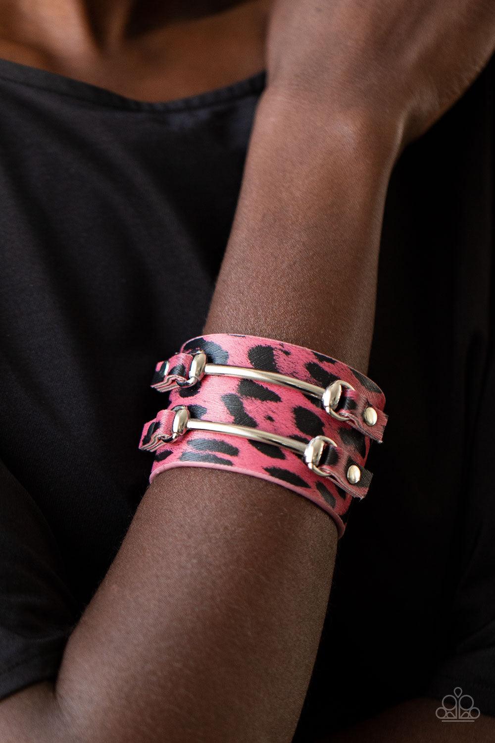 Paparazzi Accessories Safari Scene - Pink Two arcing silver bars are studded in place across the front of a thick leather band painted in pink and black cheetah print for a wild look. Features an adjustable snap closure. Sold as one individual bracelet. J