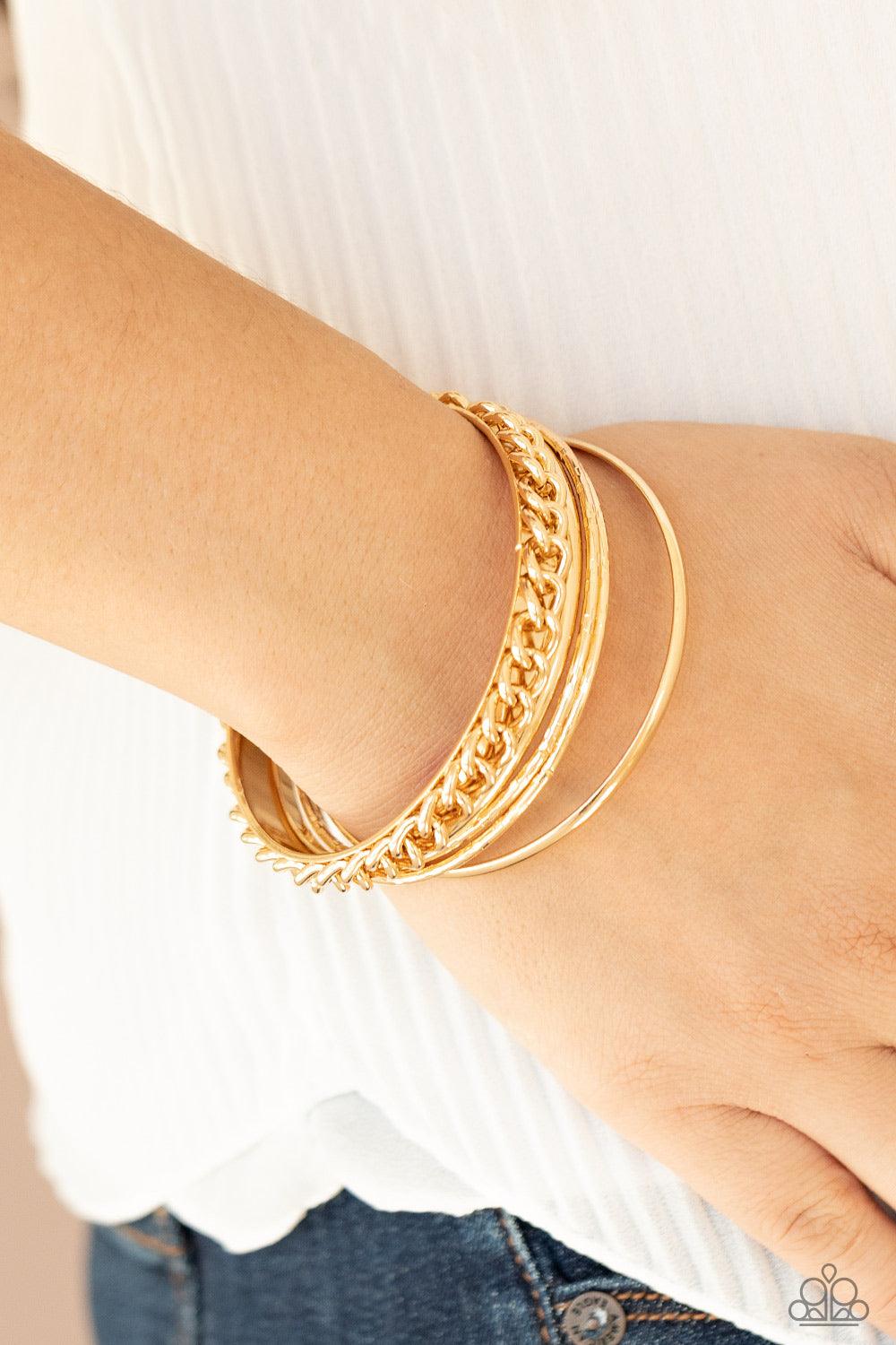 Paparazzi Accessories A Piece of The Action - Gold Pairs of smooth and textured gold bangles join a gold bangle around the wrist that is decorated in a single strand of gold chain for a gritty finish. Sold as one set of five bracelets. Jewelry