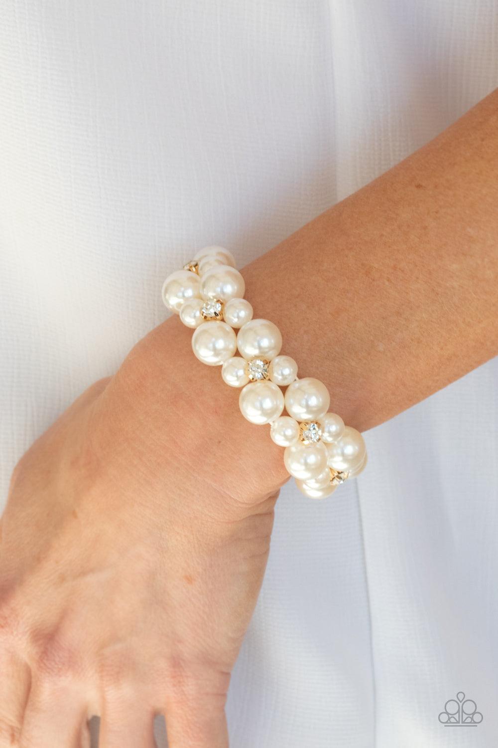 Paparazzi Accessories Flirt Alert - Gold A bubbly collection of white pearls and classic white rhinestone encrusted gold frames are threaded along stretchy bands around the wrist, creating flirtatious refinement. Sold as one individual bracelet. Bracelets