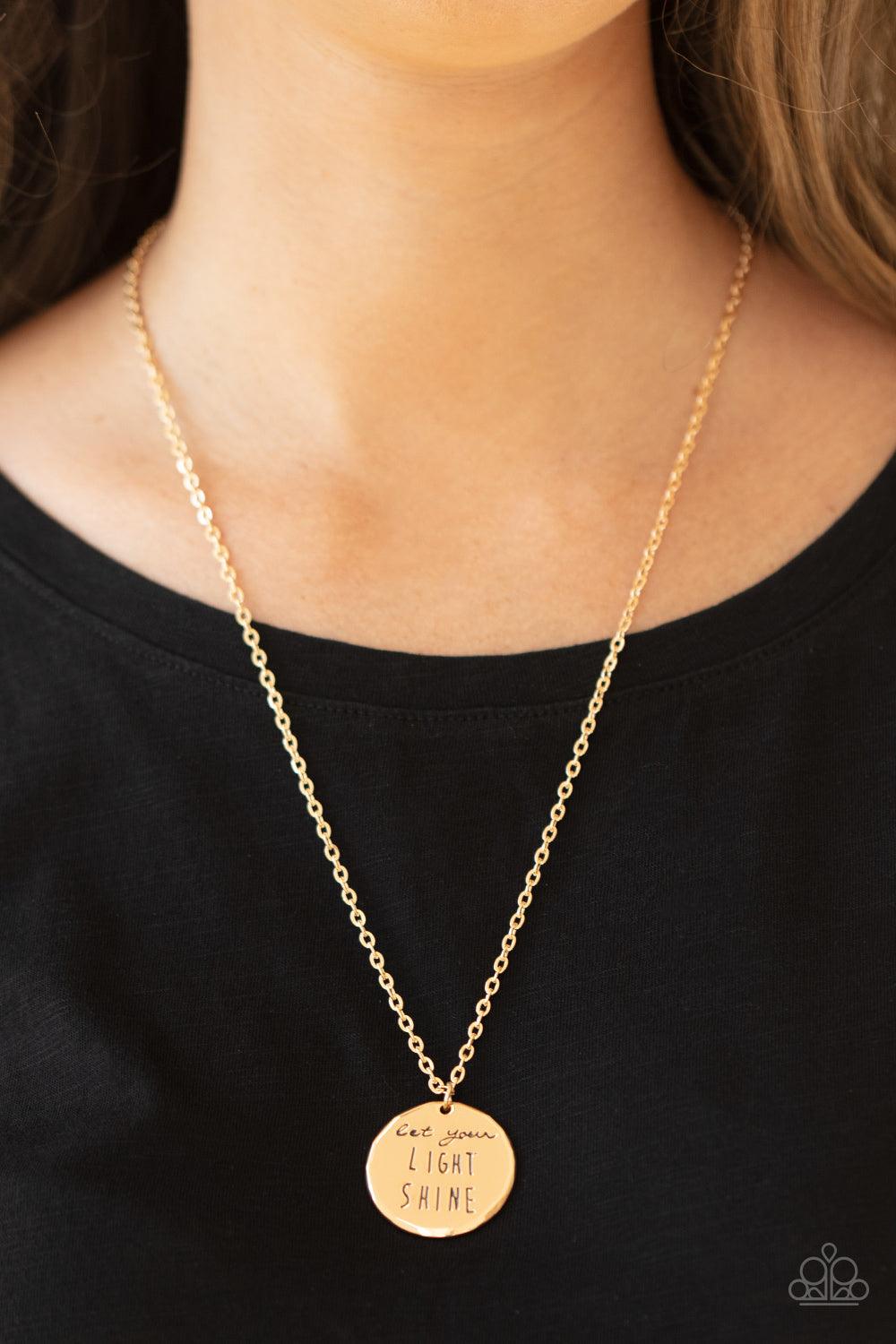 Paparazzi Accessories Light It Up - Gold A glistening gold disc is stamped in the inspiring phrase, "Let your light shine," at the bottom of a shiny gold chain. Features an adjustable clasp closure. Sold as one individual necklace. Includes one pair of ma