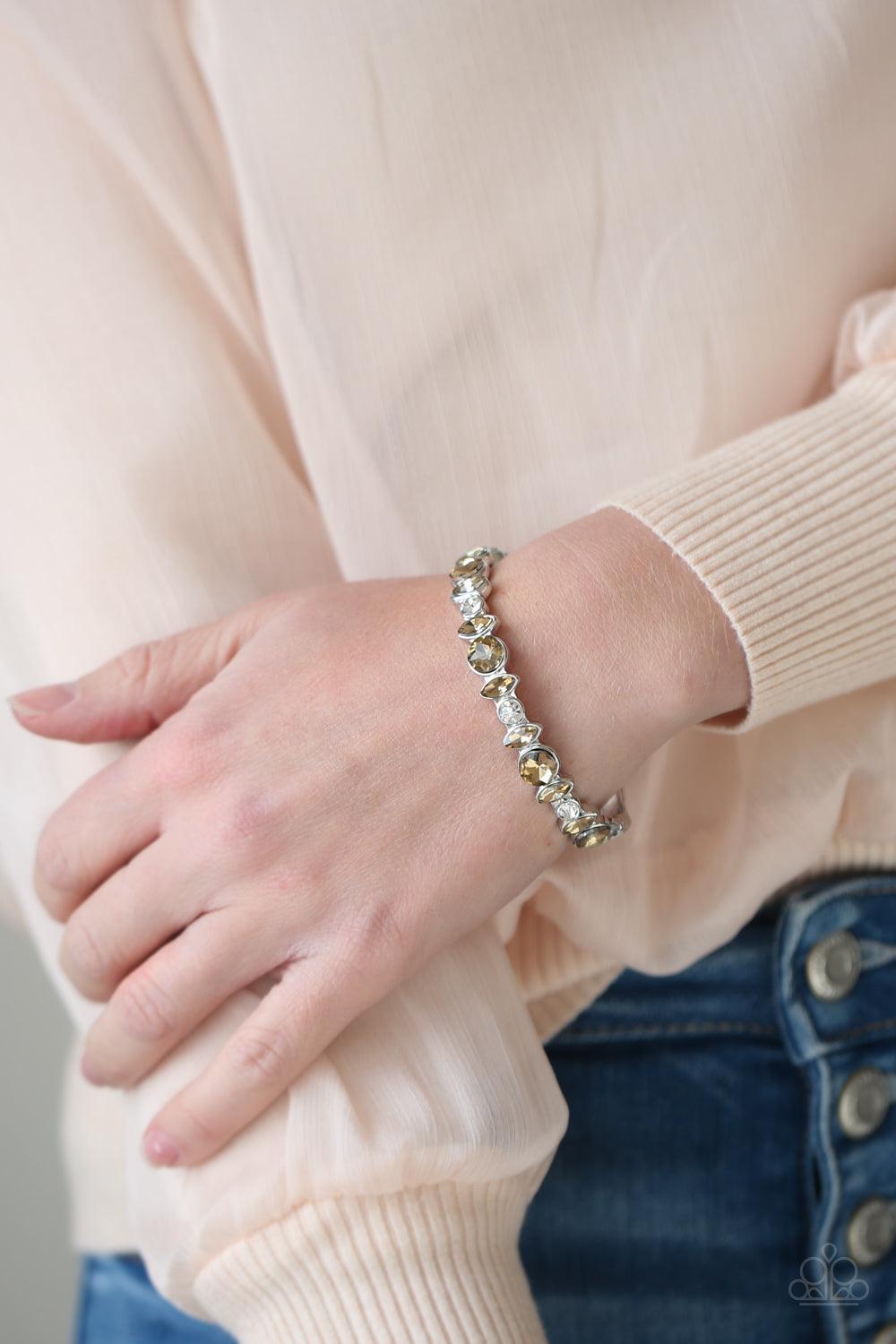 Paparazzi Accessories BLING Them To Their Knees - Brown A blinding collection of round and marquise-cut golden topaz and white rhinestones are encrusted across the front of a shiny silver bar, curling around the wrist to create a timeless cuff-like bangle