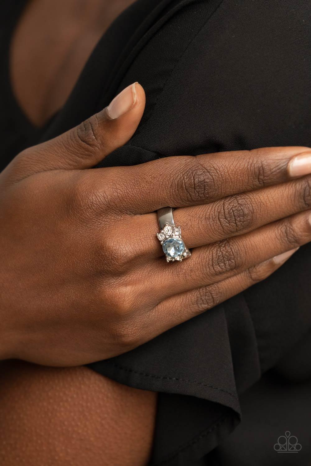 Paparazzi Accessories ROYAL Till The End - Blue Trios of glassy white rhinestones flank an oversized Cerulean rhinestone, creating a sparkly centerpiece atop a dainty silver band. Features a dainty stretchy band for a flexible fit. Sold as one individual