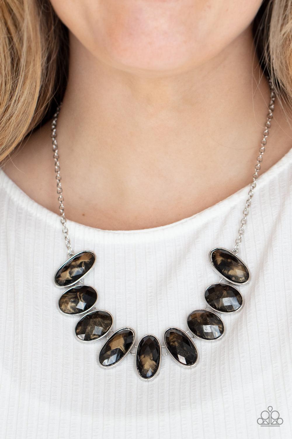 Paparazzi Accessories Elliptical Episode - Black Generous glossy black gems, dusted in shimmery gold, lay in silver oval frames and link across the collar creating a glimmering statement. Features an adjustable clasp closure. Sold as one individual neckla