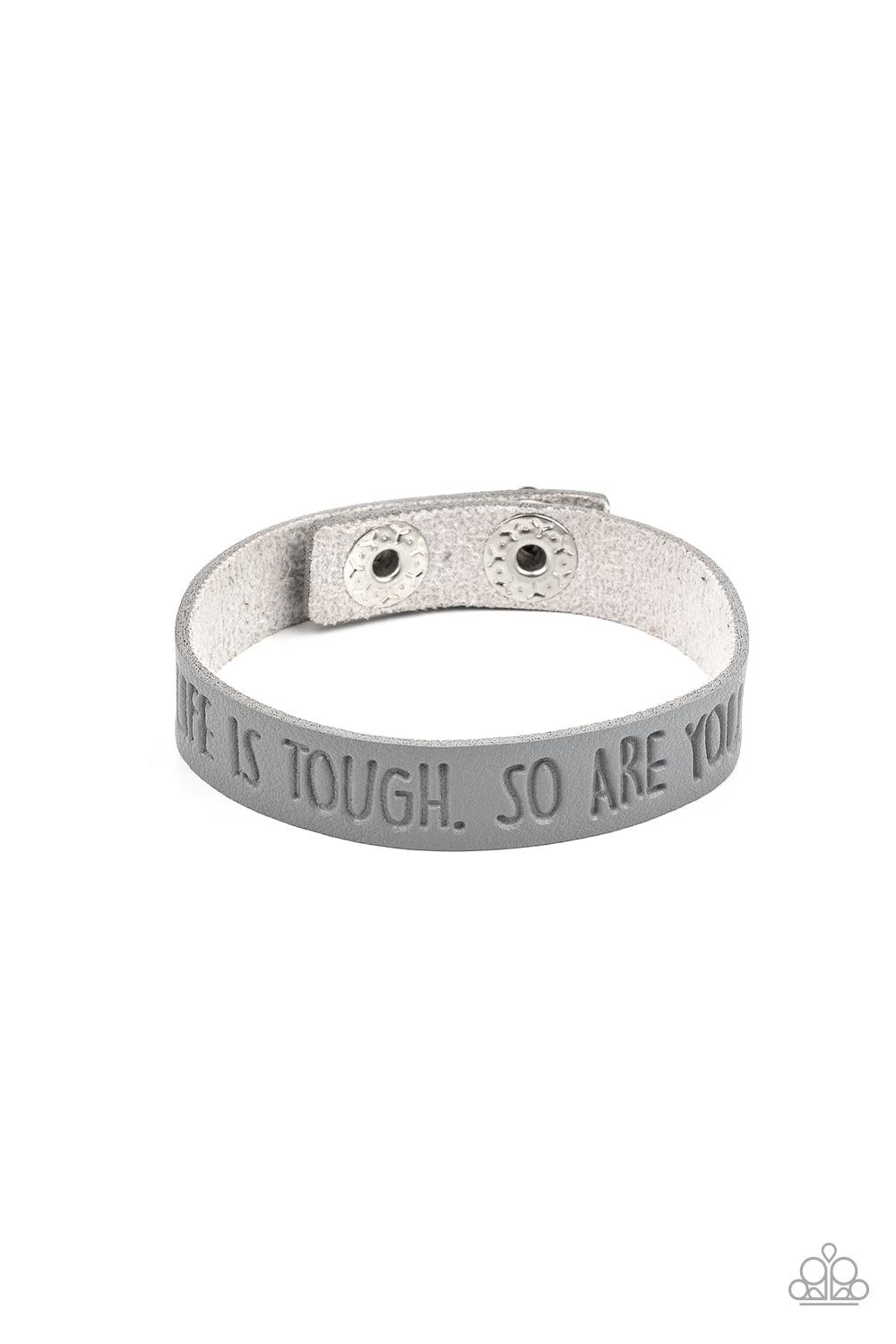 Paparazzi Accessories Life is Tough - Silver A dainty gray leather band is stamped in the phrase, "Life is tough. So Are You.," creating an inspiring centerpiece around the wrist. Features an adjustable snap closure. Sold as one individual bracelet. Jewel
