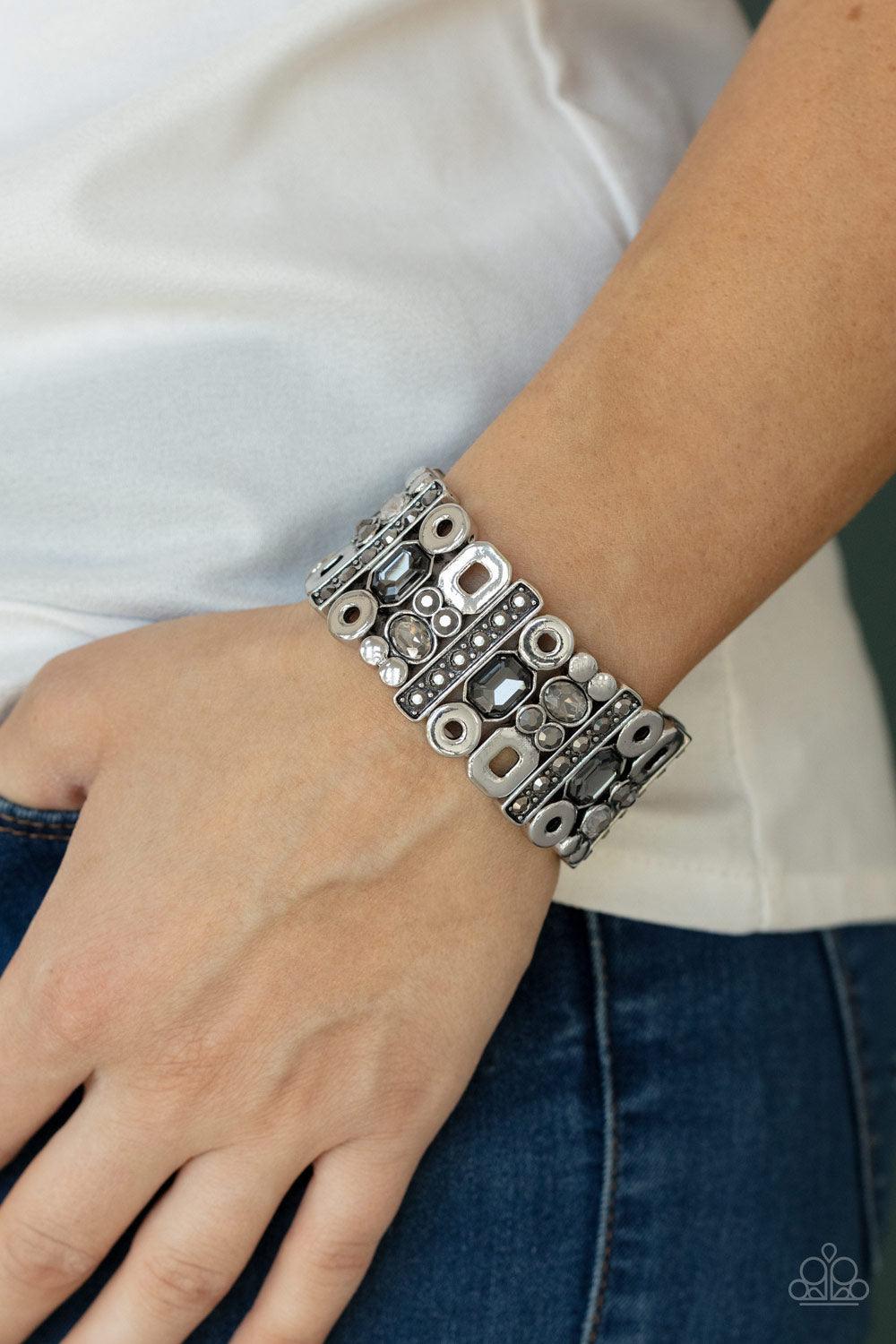 Paparazzi Accessories Dynamically Diverse - Silver Infused with flat silver studs and geometric silver accents, a mismatched assortment of oval, round, and emerald style hematite and smoky rhinestones coalesce into edgy frames along a stretchy band for an