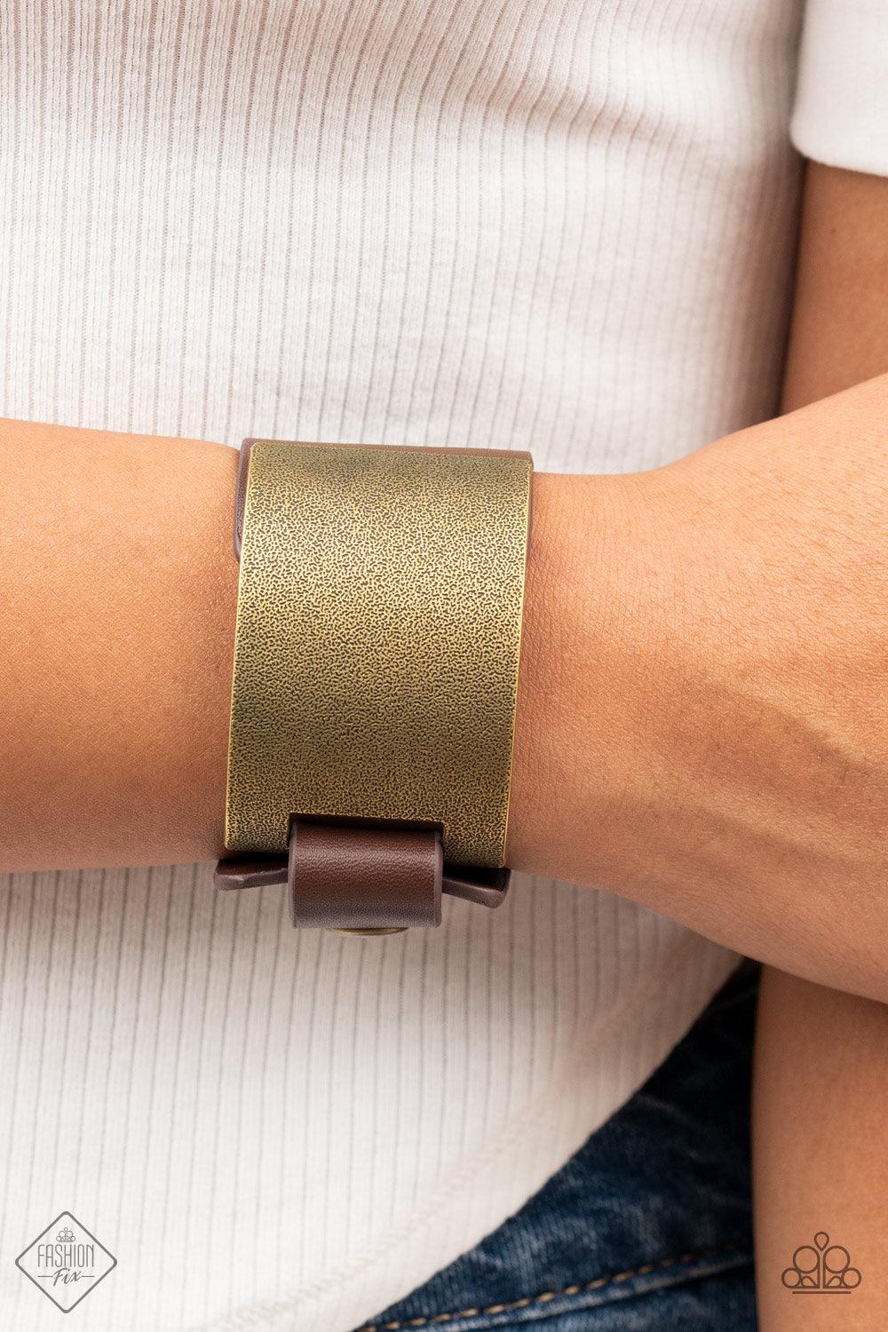 Paparazzi Accessories Studded Synchronism - Brass A curved brass panel, coated in antiqued texture, attaches to a wide brown leather band with brass snaps resulting in an edgy industrial element around the wrist. Features an adjustable snap closure. Sold
