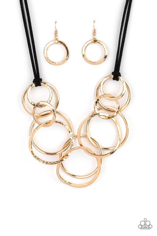 Paparazzi Accessories Spiraling Out of COUTURE - Gold Black suede cords knot around a mismatched assortment of hammered gold rings that interlock below the collar, creating two rows of dizzying texture. Features an adjustable clasp closure. Sold as one in