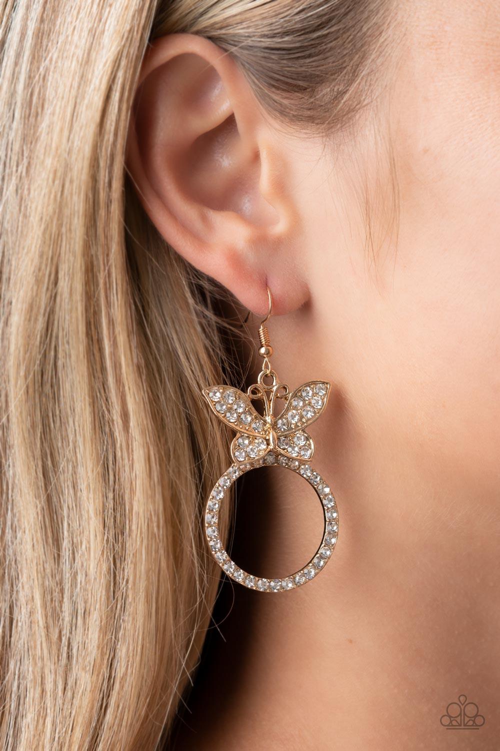 Paparazzi Accessories Paradise Found - Gold A white rhinestone encrusted gold butterfly flutters atop a gold ring dotted in matching white rhinestones, resulting in a dazzling statement piece. Earring attaches to a standard fishhook fitting. Sold as one p