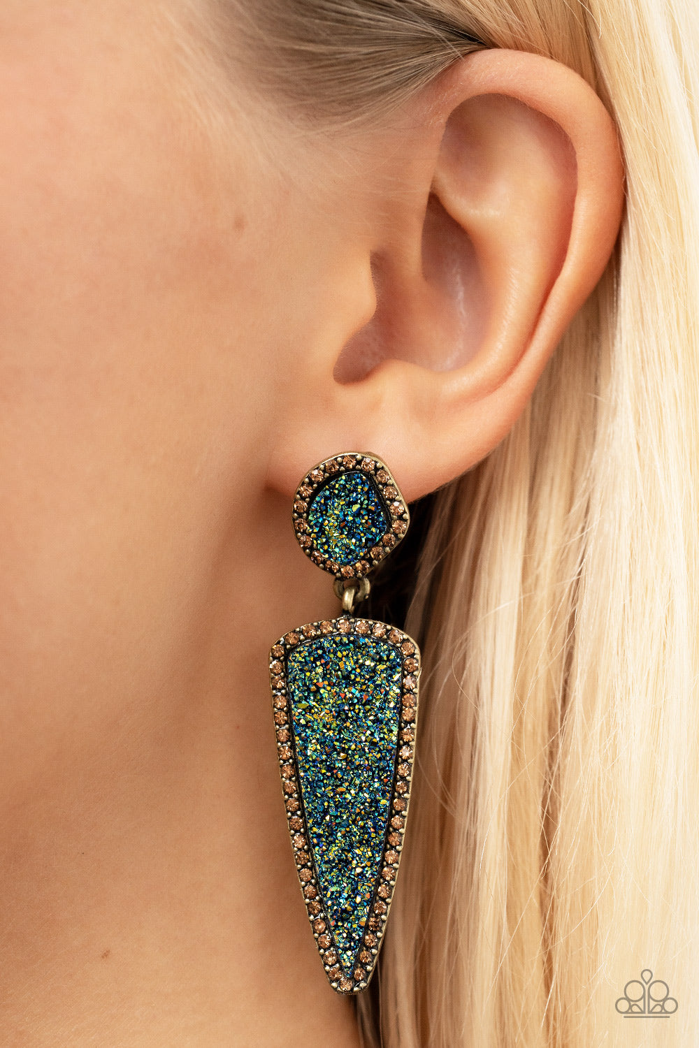 Paparazzi Accessories Druzy Desire - Brass Featuring asymmetrical and triangular cuts, a pair of blue druzy-like accents are encased inside topaz rhinestone dotted brass frames as they link into a jaw-dropping lure. Earring attaches to a standard post fit
