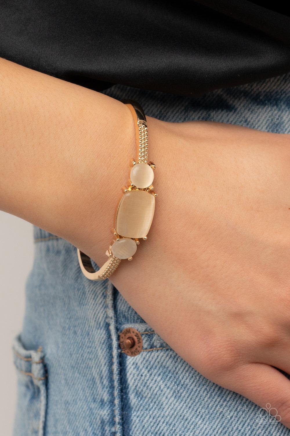 Paparazzi Accessories Tranquil Treasure - Gold A rectangular golden cat's eye stone is flanked by a pair of golden cat's eye stones atop a textured gold cuff, resulting in a dainty pop of color atop the wrist. Sold as one individual bracelet. Bracelets