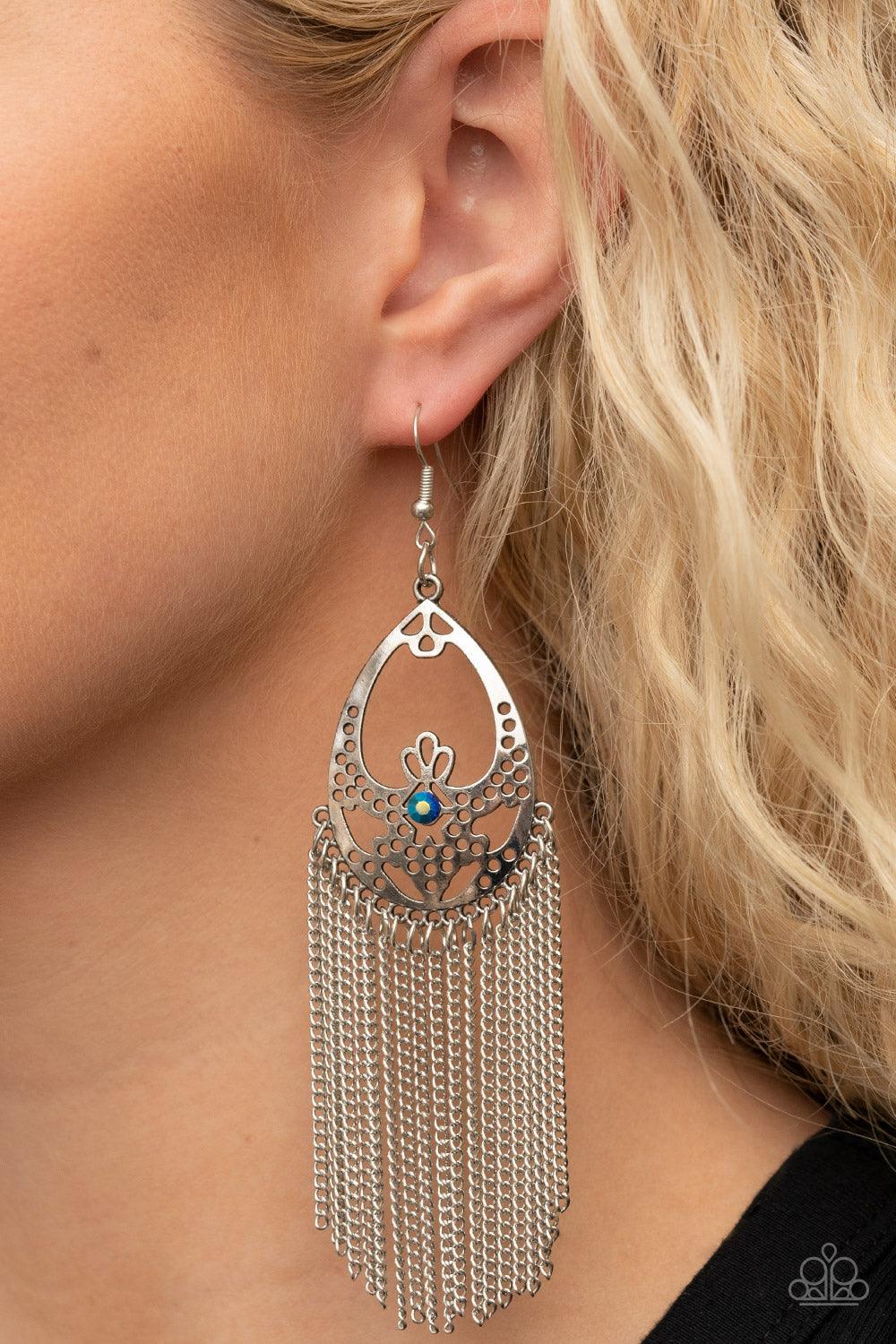Paparazzi Accessories Castle Cottage - Blue An antiqued curtain of silver chains streams from the bottom of an airy stenciled silver oval frame. An iridescent blue rhinestone adorns the center of the whimsical frame, adding a mystical pop of color to the