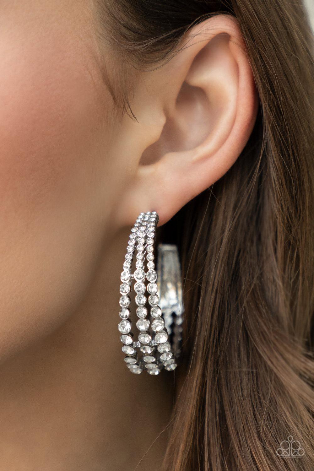 Paparazzi Accessories Cosmopolitan Cool - White Cascading layers of sparkling white rhinestones plunge into flattened silver plates creating a stunning eye-catching hoop earring. Earring attaches to a standard post fitting. Hoop measures approximately 2"