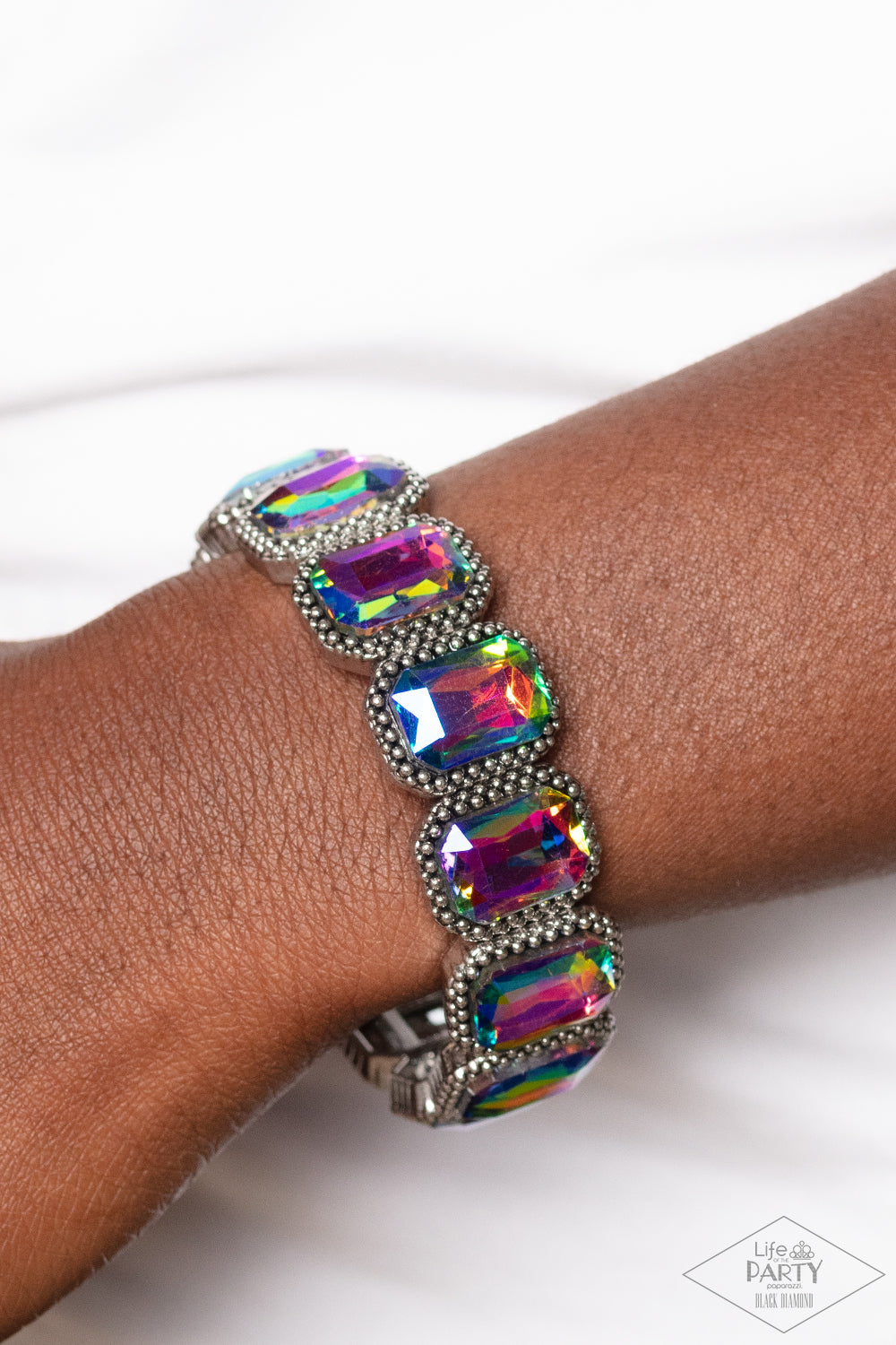 Paparazzi Accessories Studded Smolder - Multi Oversized emerald style oil spill gems are encased in antiqued studded frames that are threaded along stretchy bands around the wrist, creating a smoldering centerpiece. Due to its prismatic palette, color may