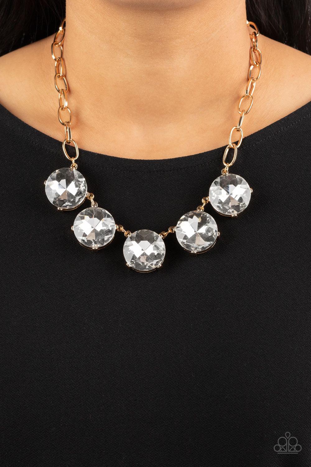 Paparazzi Accessories Limelight Luxury - Gold Set in gold pronged fittings, five dramatically oversized white rhinestones connect across the collar and attach to an oversized gold chain creating a stunning spot-light loving statement piece. Features an ad