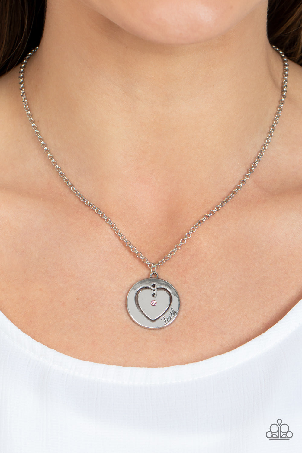 Paparazzi Accessories Heart Full of Faith - Pink Dotted with a dainty pink rhinestone, a silver heart charm swings freely inside of a heart-cutout silver frame. Stamped in the word, "Faith," the inspirational pendant falls just below the collar for a sent