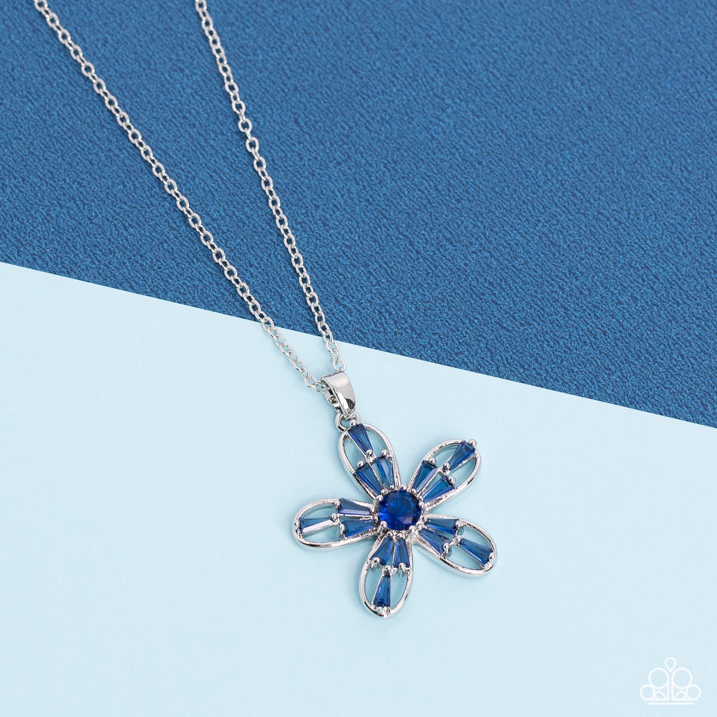 Paparazzi Accessories Botanical Ballad - Blue Emerald cut Skydiver rhinestones are scattered across the front of airy silver petals that bloom from a Skydiver rhinestone center, resulting in a sparkly floral pendant below the collar. Features an adjustabl