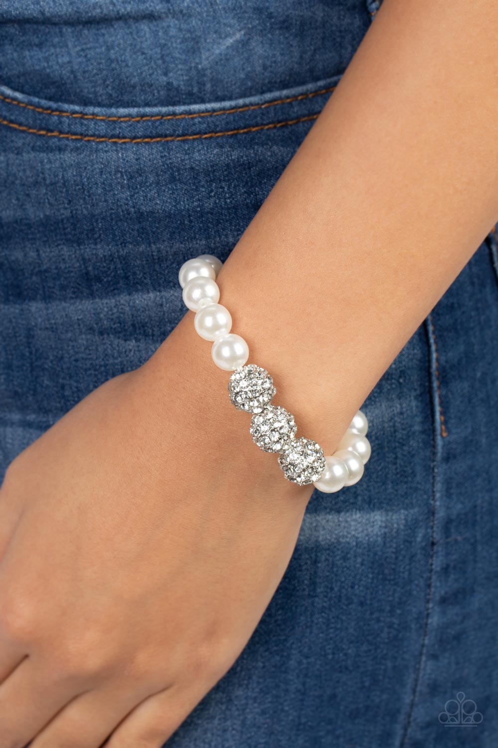 Paparazzi Accessories Breathtaking Ball - White A trio of silver beads encrusted in rhinestones is centered along a strand of classic white pearls. The beads are threaded along a stretchy band, wrapping around the wrist in a refined finish. Sold as one in
