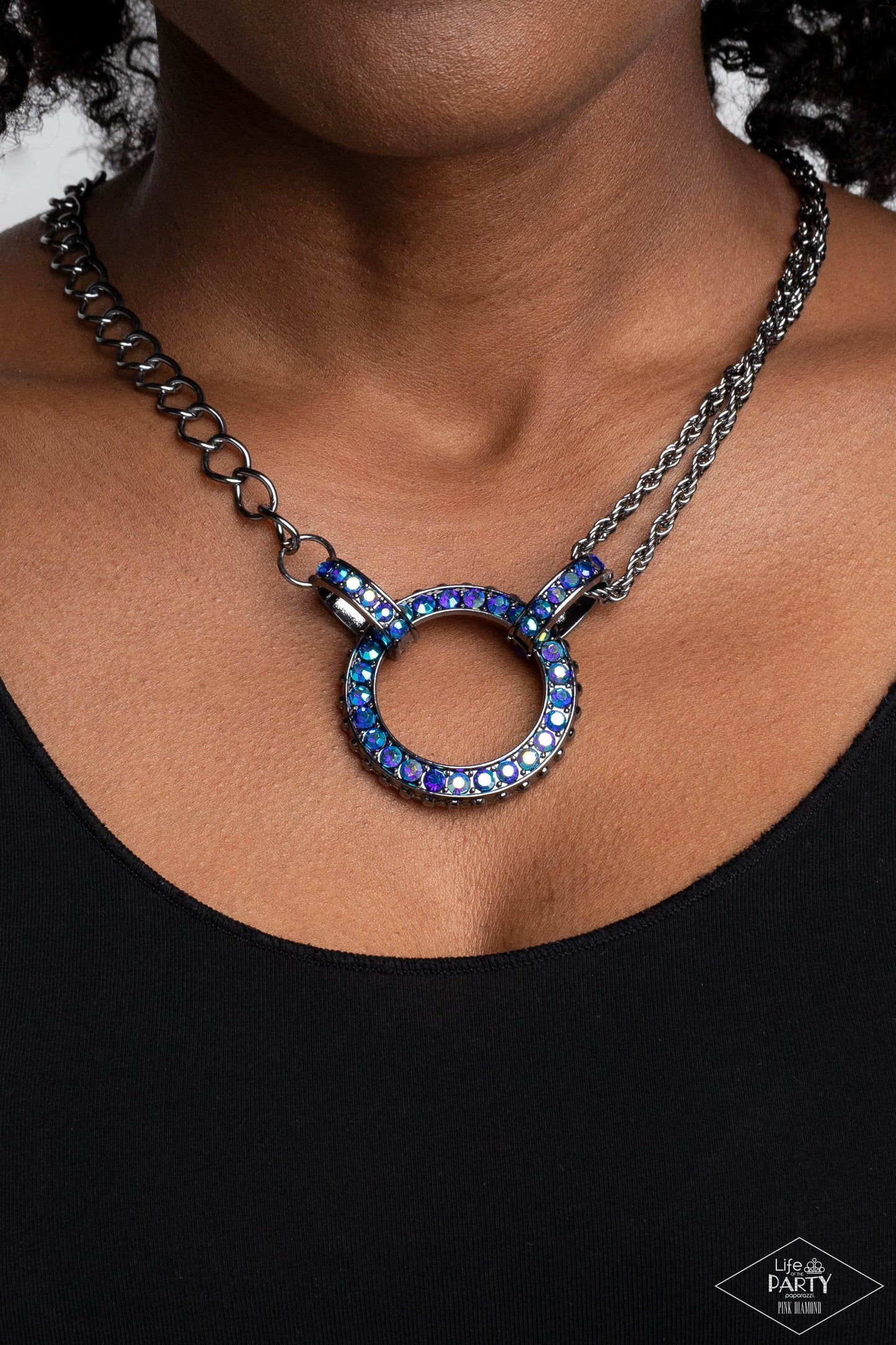 Paparazzi Accessories Razzle Dazzle - Blue A collision of mismatched gunmetal chains gives way to a studded gunmetal pendant that has been encrusted in glittery blue UV rhinestones. The result is a gritty, industrial design with endless attitude. Features