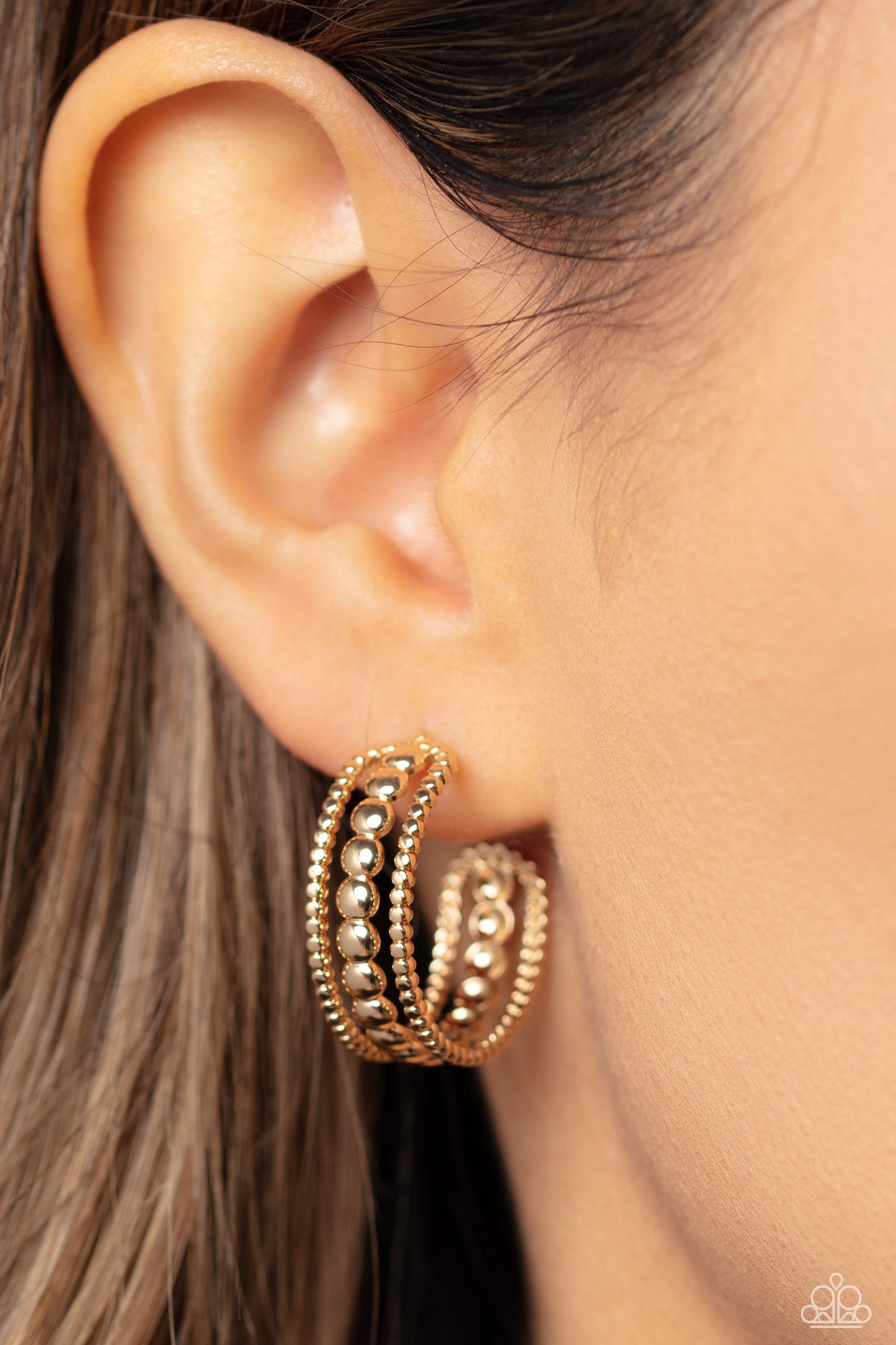 Paparazzi Accessories Dotted Darling - Gold A row of high-sheen gold studs runs down the center of an airy gold hoop for an edgy look. Layering against the centermost studs, smaller gold studs grace both sides of the hoop creating additional eye-catching