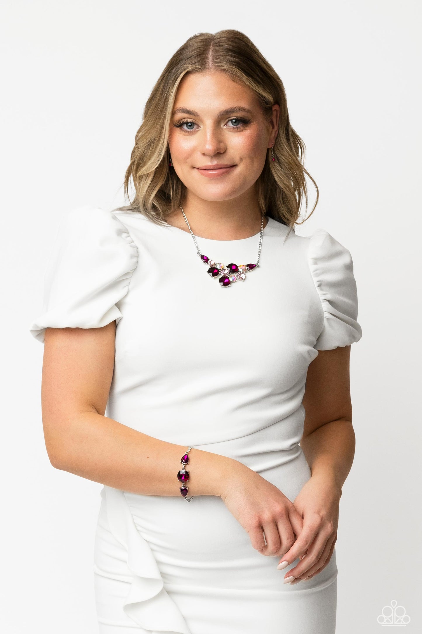 Paparazzi Accessories Twinkling Trio - Pink An oversized round gem bordered by teardrop gems cluster together to create a glittery silver collection around the wrist. Featured in a fuchsia hue, each gem reflects light off of its faceted surface emitting f