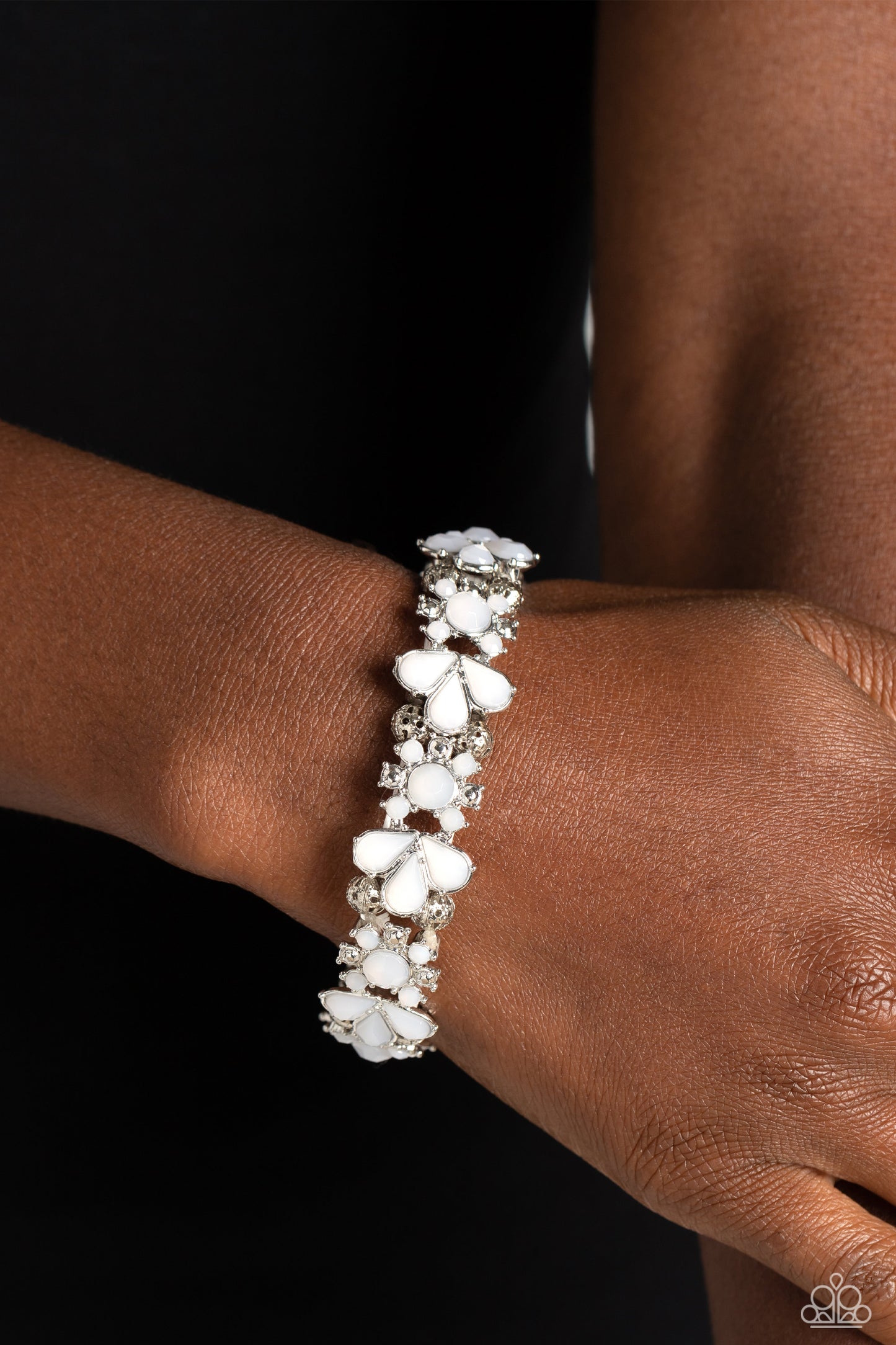 Paparazzi Accessories Teasing Torrent - White A flourishing opaque collection of white round and teardrop beads coalesce into abstract floral-inspired frames. Separating each floral frame, airy, silver-studded beads are infused along elastic stretchy band
