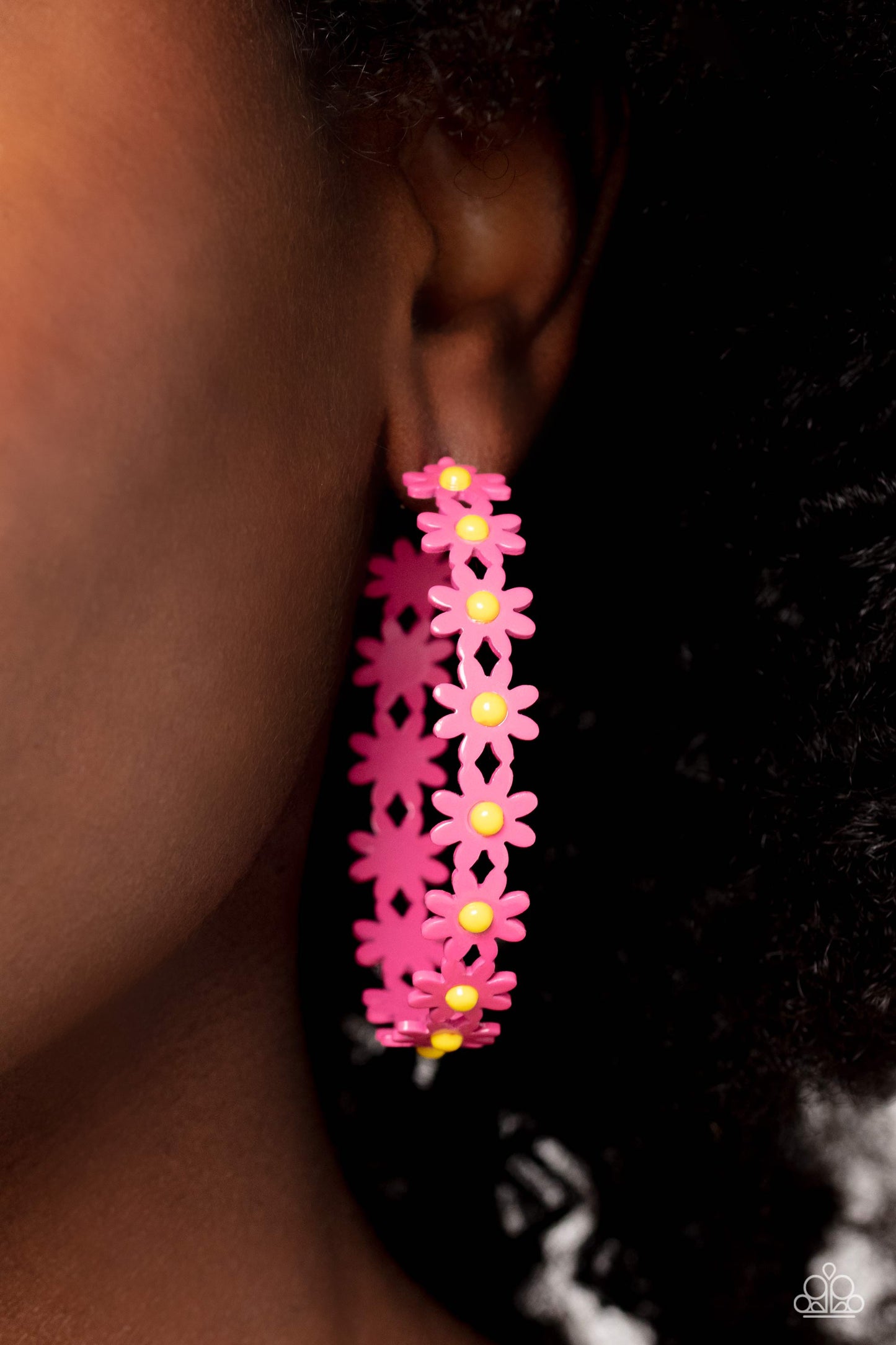 Paparazzi Accessories Daisy Disposition - Pink A dainty collection of hot pink daisies with yellow centers blooms into a free-spirited hoop around the ear. Earring attaches to a standard post fitting. Hoop measures approximately 2" in diameter. Sold as on