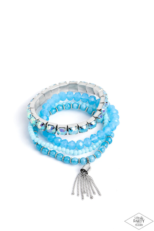 Paparazzi Accessories Day Trip Trinket - Blue Pinched in silver fittings, a band of UV shimmery Waterspout beads joins mismatched strands of smoky, glassy, and faceted blue beads creating four stretchy bracelets around the wrist. A single silver chain tas