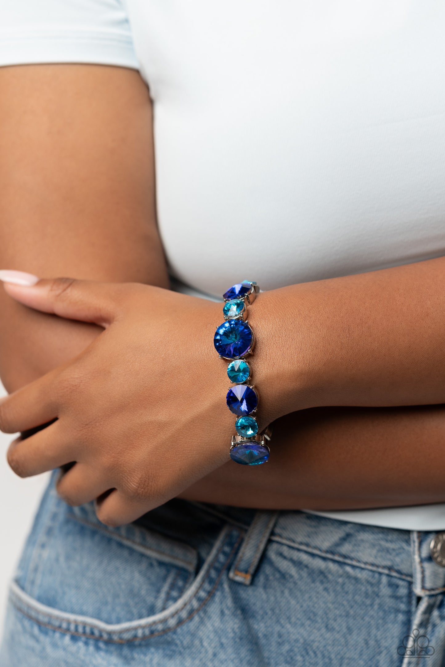 Paparazzi Accessories Refreshing Radiance - Blue Pressed in silver-pronged frames, vibrant blue gems in varying sizes and shades alternate along stretchy bands around the wrist, creating a colorful pop of color. The larger blue gems feature a stellar UV s