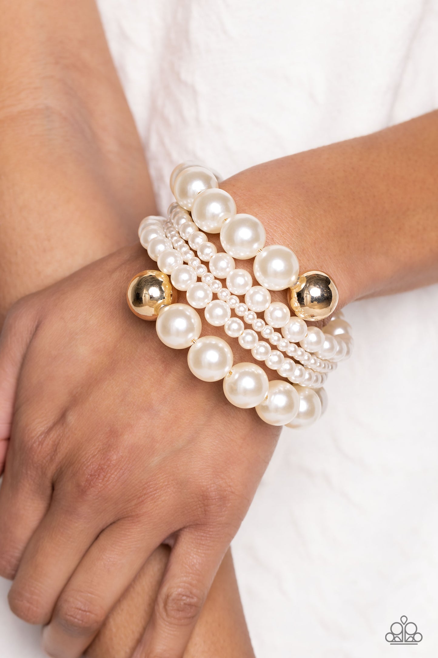 Paparazzi Accessories Pleasing Pirouette - Gold Varying sizes of lustrous pearls are threaded along a wire that curves and spins around the wrist, creating an elegant infinity wrap style bracelet. Reflective gold beads border the ends of the pearly displa
