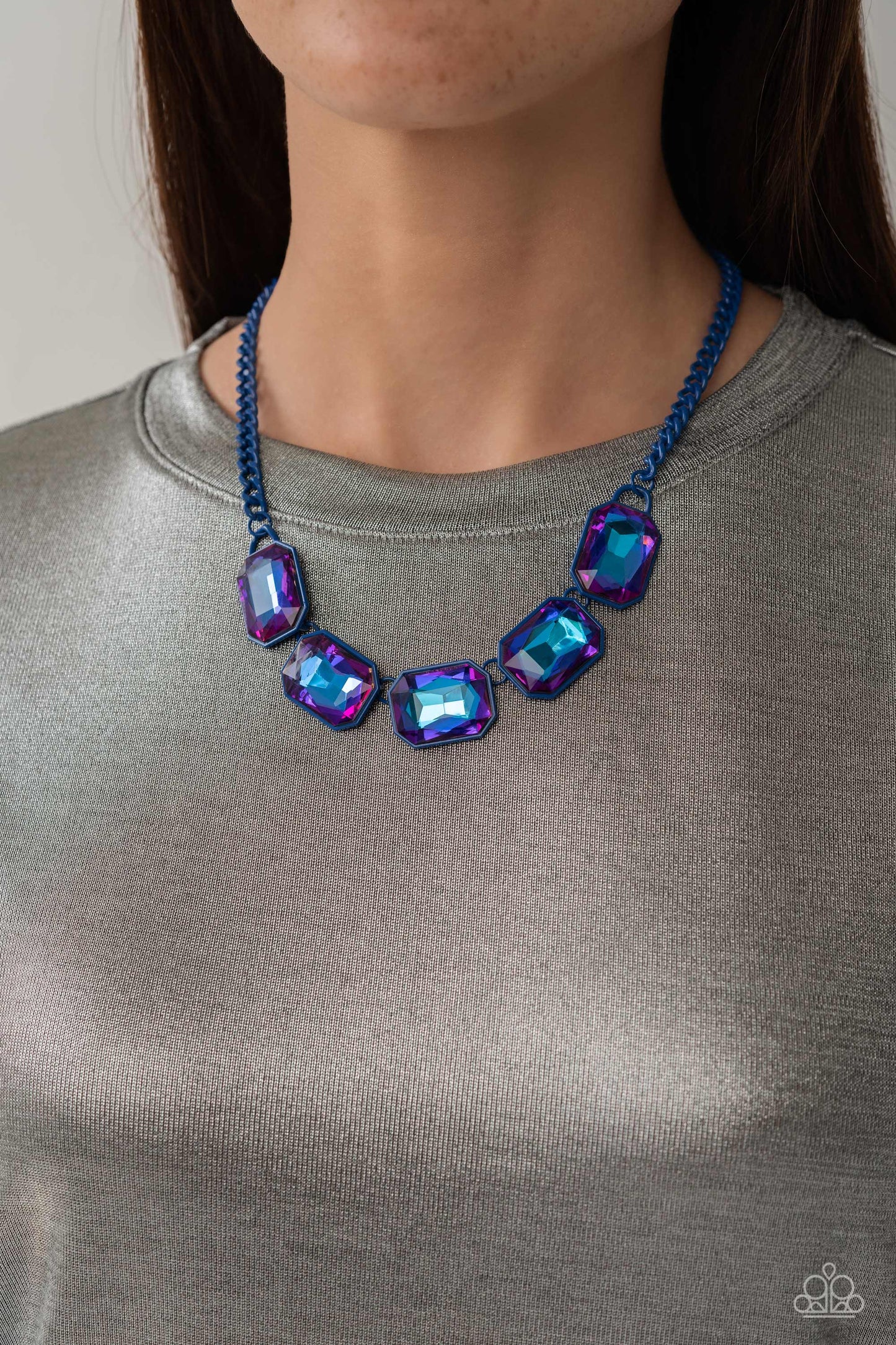 Paparazzi Accessories Emerald City Couture - Blue Featuring a vivacious blue chain, a collection of purple UV shimmery emerald-cut gems, pressed in vibrant blue frames, coalesces around the collar to create a playful pop of edgy color. Features an adjusta