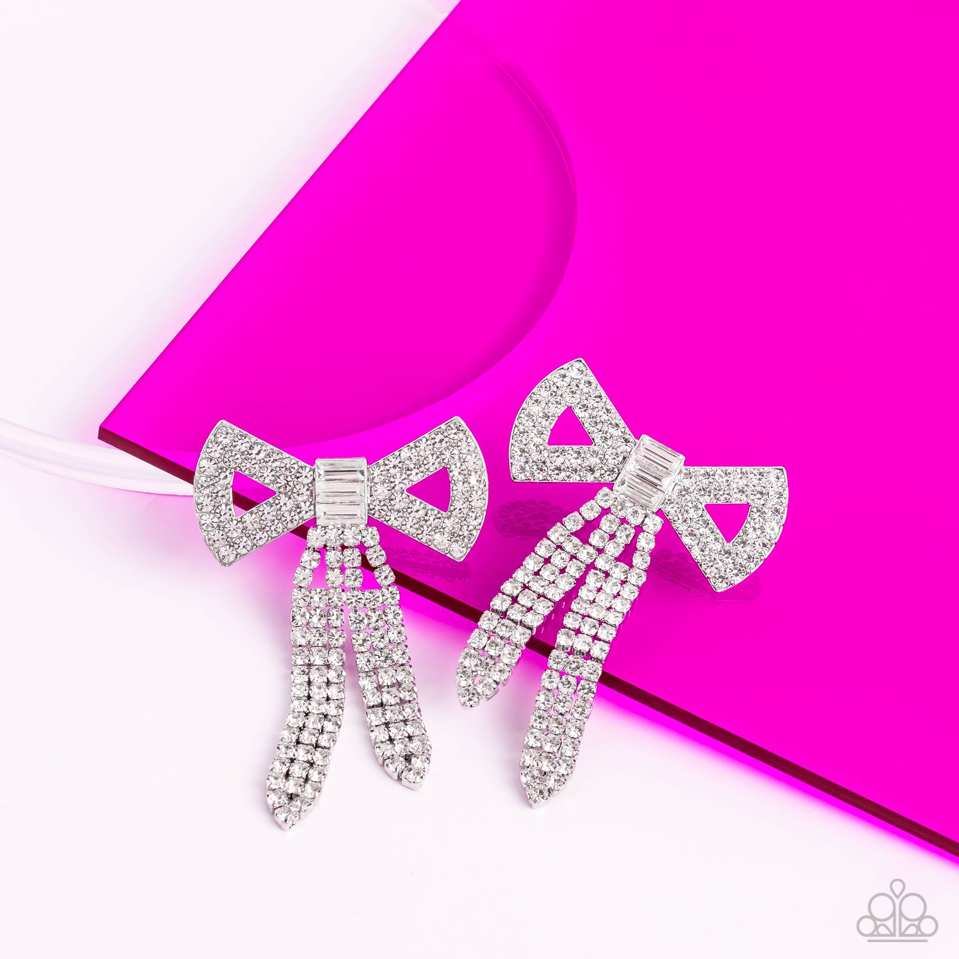 Paparazzi Accessories Just BOW With It - White Featuring silver square fittings, high-sheen bands of silver, adorned in sparkling white rhinestones loop into a stunning bow charm, creating a classy statement at the ear. Featured in the center of the class
