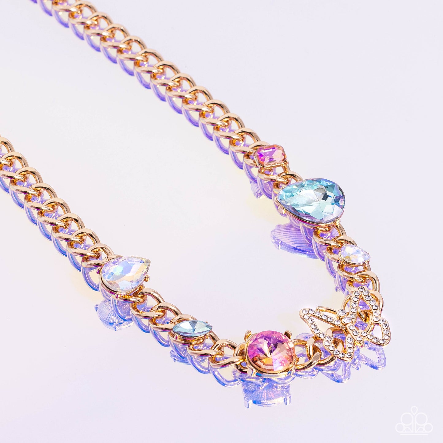 Paparazzi Accessories Storybook Succession - Gold A succession of various gleaming, multicolored gems encased in gold fittings are affixed to a high-sheen, thick gold curb chain, adding dramatic dimension and color to an industrial statement. An airy gold
