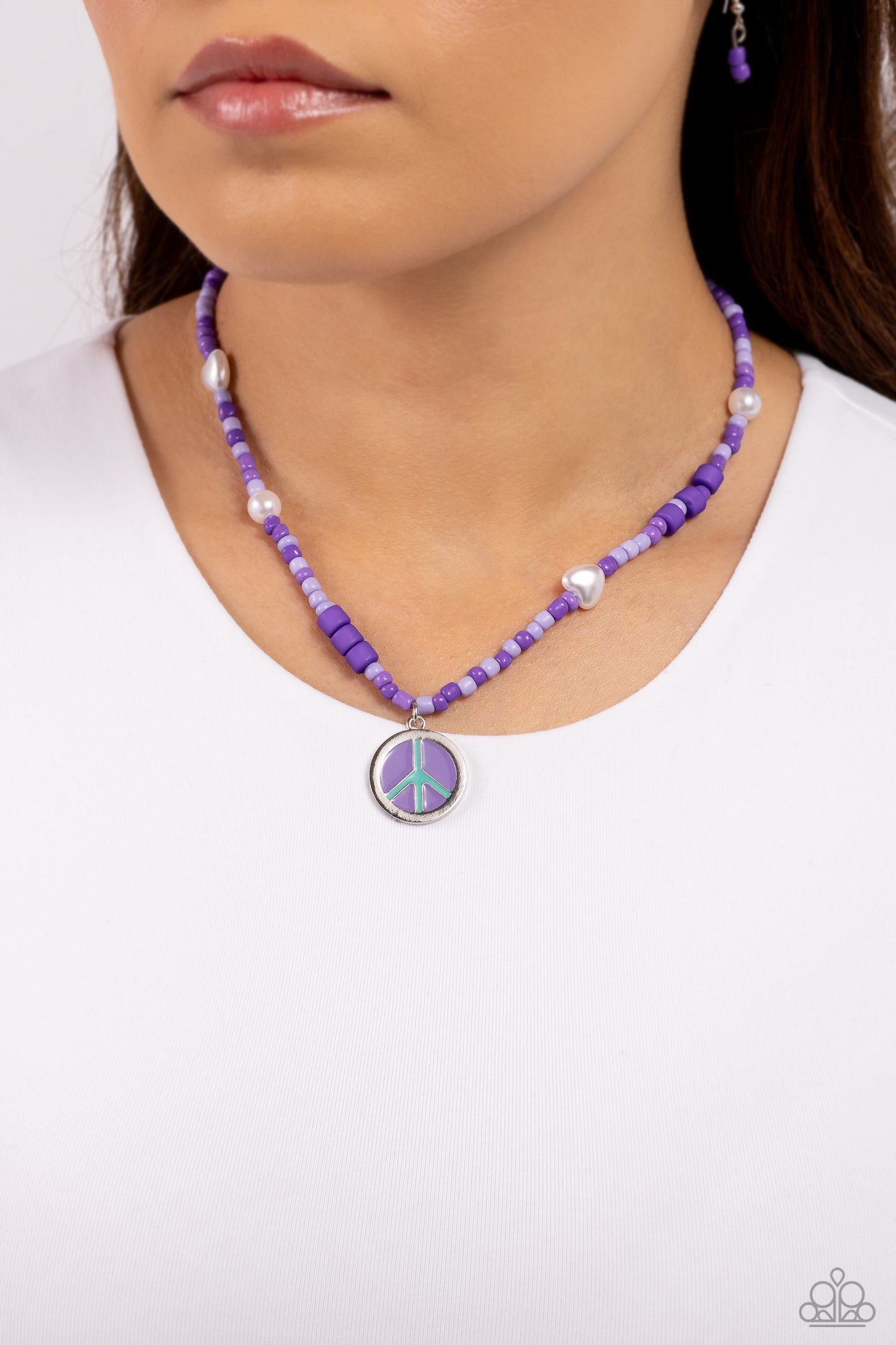 Paparazzi Accessories Pearly Possession - Purple Infused along an invisible string, lavender, plum, and purple seed beads combine with sporadically placed purple discs, and glossy white and heart-shaped pearls for a vibrant pop of color along the neckline