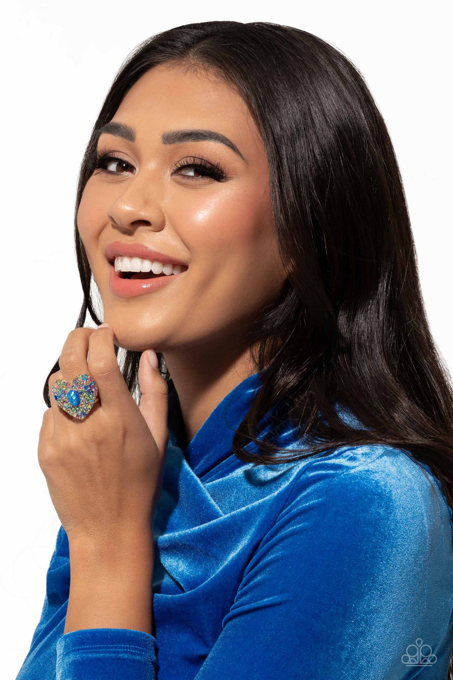 Paparazzi Accessories Bejeweled Beau - Blue Encrusted in brilliant multicolored and iridescent rhinestones, a glittery gold heart frame adorns the center of an airy gold band for a flirtatious finish. Featuring iridescent flecks, an opalescent blue oval b