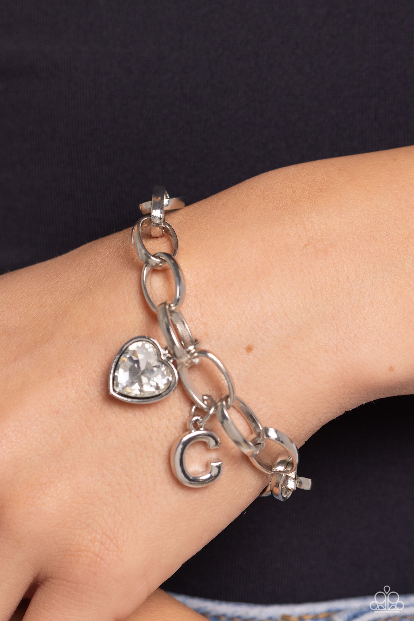 Paparazzi Accessories Guess Now Its INITIAL - White - C A simple collection of silver charms — including a white rhinestone heart pressed in a silver frame and a sleek letter "C" — dance from a chunky silver chain around the wrist, creating a sentimental