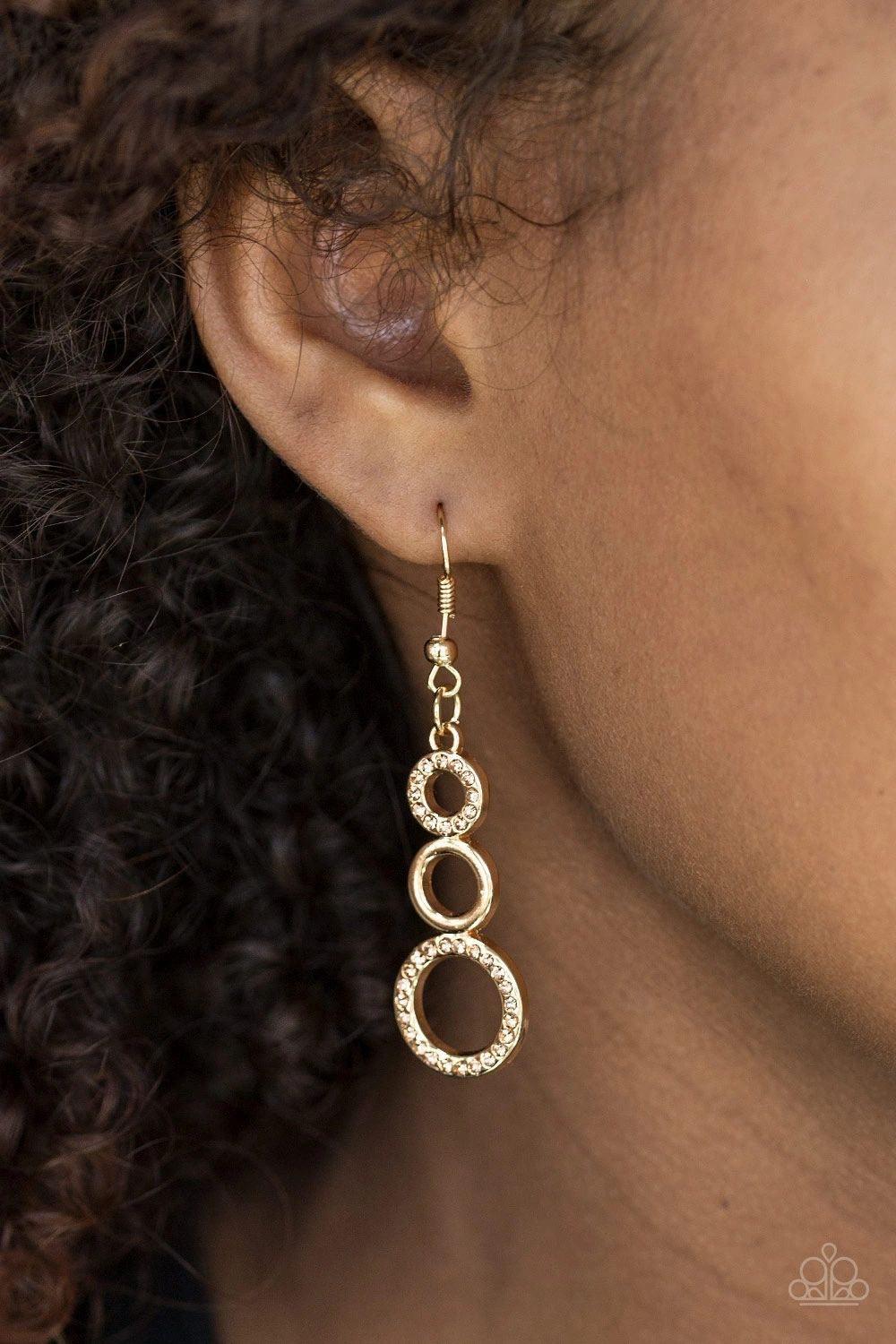 Paparazzi Accessories Bubble Bustle - Gold Alternating in glittery rhinestones, shiny gold circles gradually increase in size as they connect into a bubbly lure. Earring attaches to a standard fishhook fitting. Jewelry