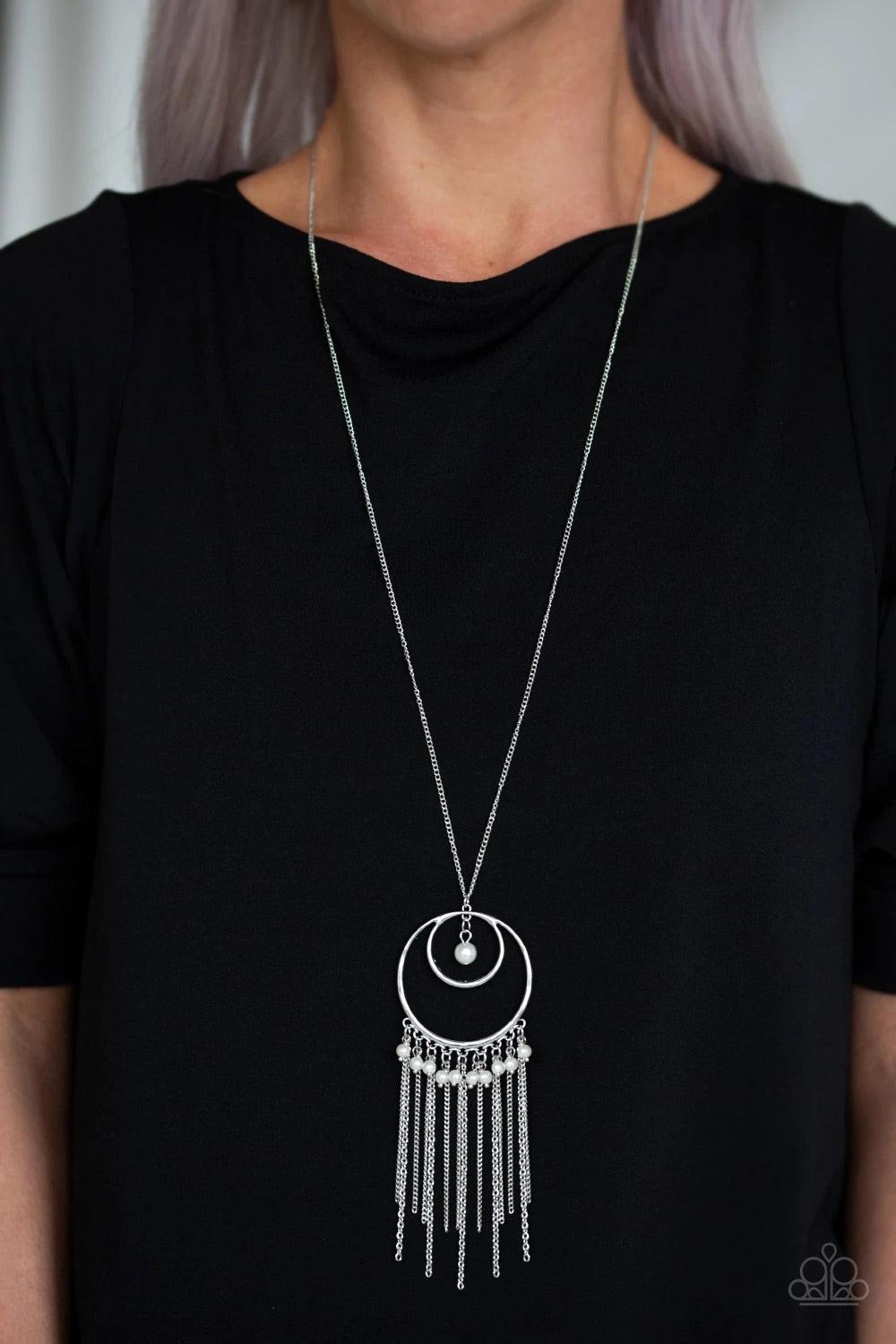 Paparazzi Accessories Out of Bounds Shimmer - White An airy circular pendant swings from the bottom of a lengthened silver chain. Infused with a solitaire white pearl swinging from the top of the frame, a fringe of white pearls and shimmery silver chains