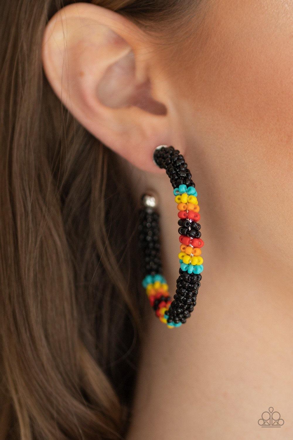 Paparazzi Accessories Bodaciously Beaded - Black A colorful strand of black, blue, yellow, orange, and red seed beads wraps around a shiny silver hoop, creating a colorfully seasonal look. Earring attaches to a standard post fitting. Hoop measures approxi