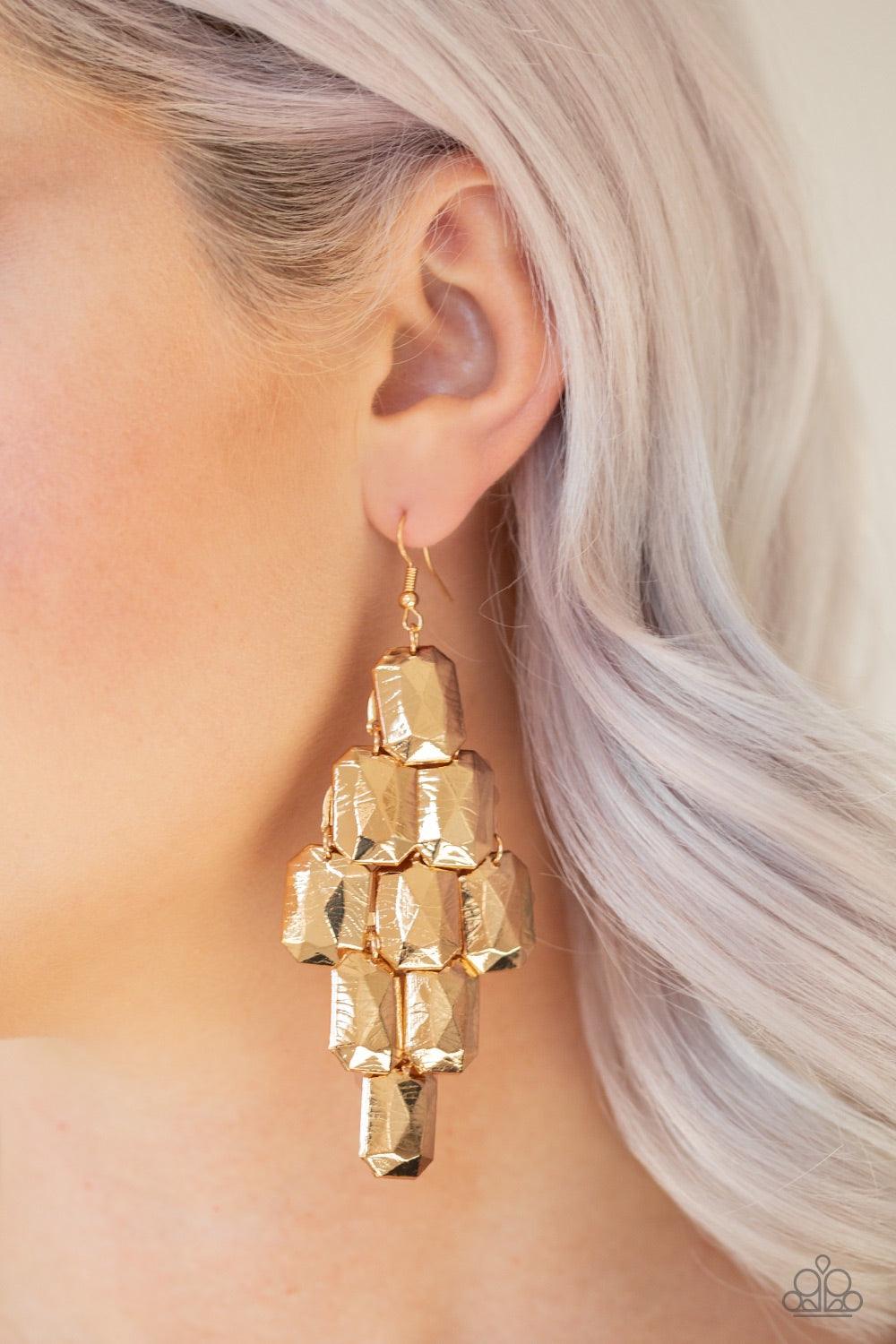 Paparazzi Accessories Contemporary Catwalk - Gold Delicately etched in linear patterns, faceted gold emerald-shaped frames cascade from the ear for a contemporary look. Earring attaches to a standard fishhook fitting. Jewelry