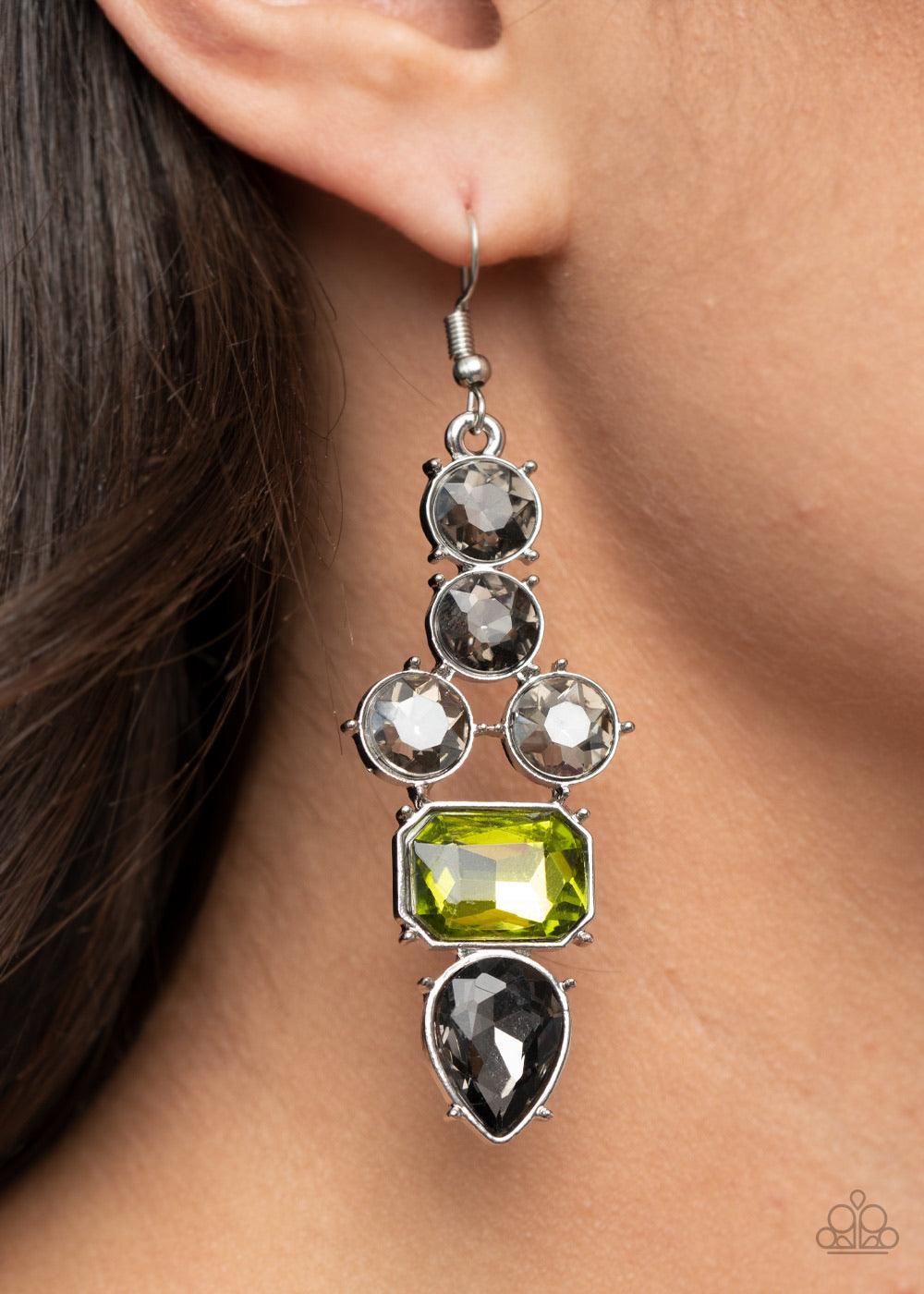 Paparazzi Accessories Look At Me GLOW! - Green Featuring emerald, round, and teardrop shapes, a sparkly series of smoky and green rhinestones coalesce into a dramatically regal lure. Earring attaches to a standard fishhook fitting. Sold as one pair of ear