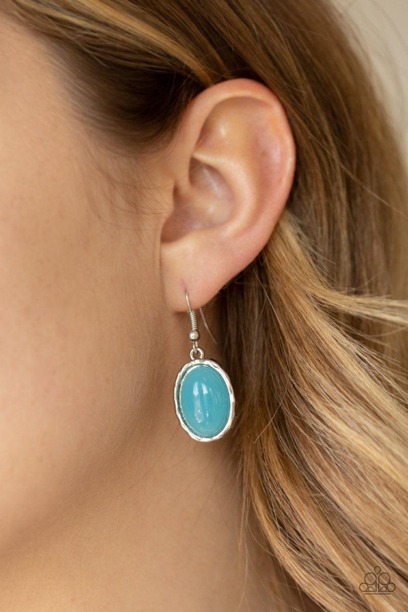 Paparazzi Accessories Harbor Harmony - Blue A dewy blue bead is pressed into the center of a stacked silver frame radiating with shimmery hammered textures. The oversized pendant swings from the bottom of a lengthened silver chain, adding a whimsical pop