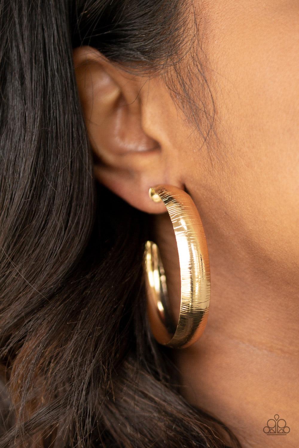 Paparazzi Accessories Hoop Wild - Gold Etched in a shimmery linear pattern, a thick gold hoop curls around the ear for some classic edge. Earring attaches to a standard post fitting. Hoop measures approximately 2" in diameter. Jewelry