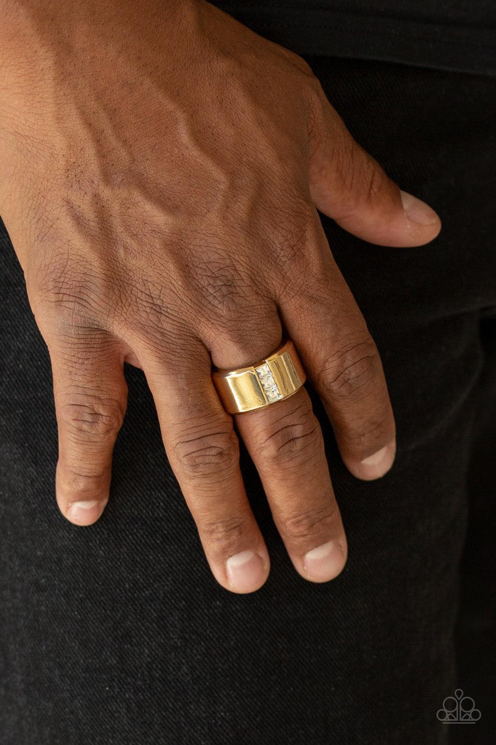 Paparazzi Accessories The Graduate - Gold A single row of square-cut white rhinestones stack down the center of a thick gold band. Features a stretchy band for a flexible fit. Jewelry