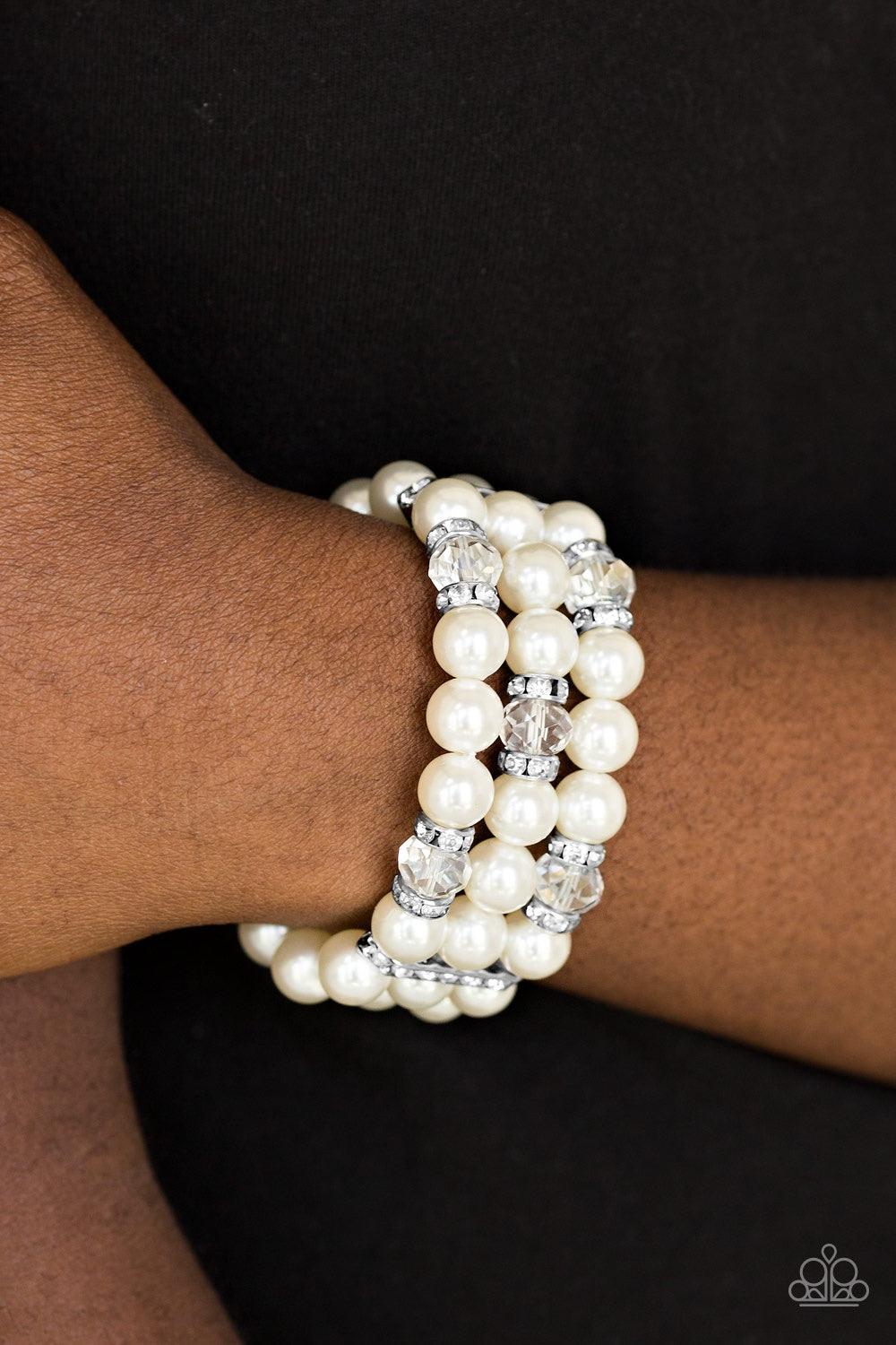 Paparazzi Accessories Undeniably Dapper - White Pinched between white rhinestone encrusted frames, white rhinestone encrusted rings, crystal-beads, and white pearls are threaded along elastic stretchy bands for a glamorous look. Jewelry