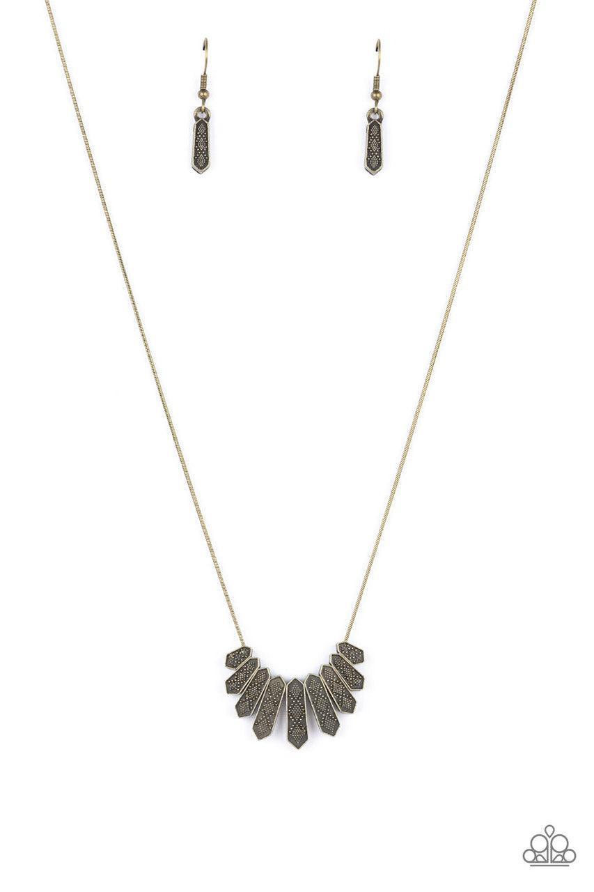 Paparazzi Accessories Monumental March - Brass A row of brass obelisk-like monuments gradually decrease in size as they fan out across the collar. Delicately embossed with textured diamond shapes, they march along a dainty round brass chain. Features an a